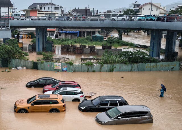 <p>A man (R) wades through floodwaters near inundated vehicles in Nha Trang, Vietnam's coastal province of Khanh Hoa on November 20, 2025</p>