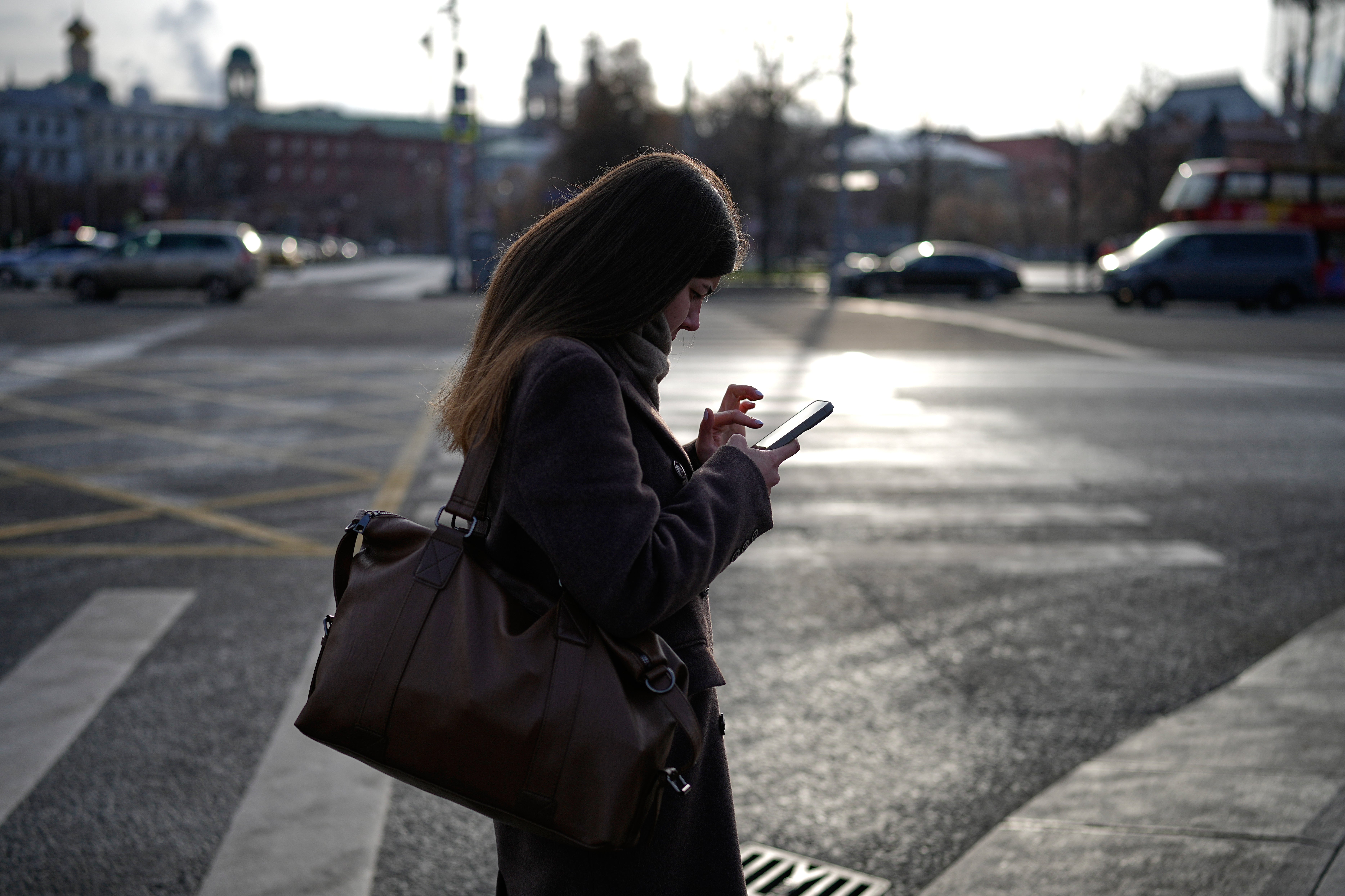 A woman looks at her smartphone in central Moscow, Russia, Thursday, Nov. 20, 2025. (AP Photo/Alexander Zemlianichenko)