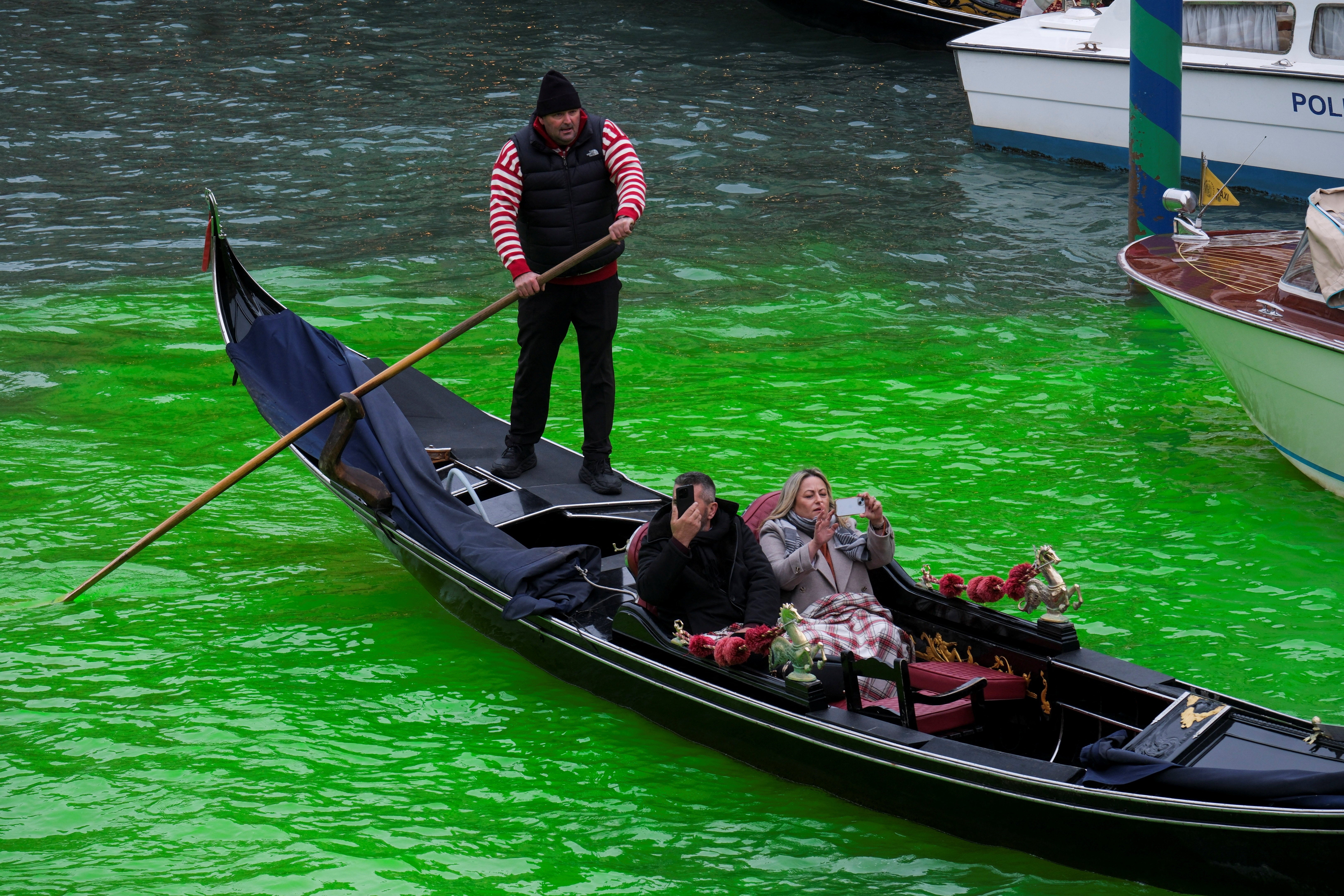 People enjoy a gondola ride on the Grand Canal, where the canal's water was dyed green