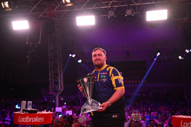 <p>Luke Littler poses with the trophy</p>