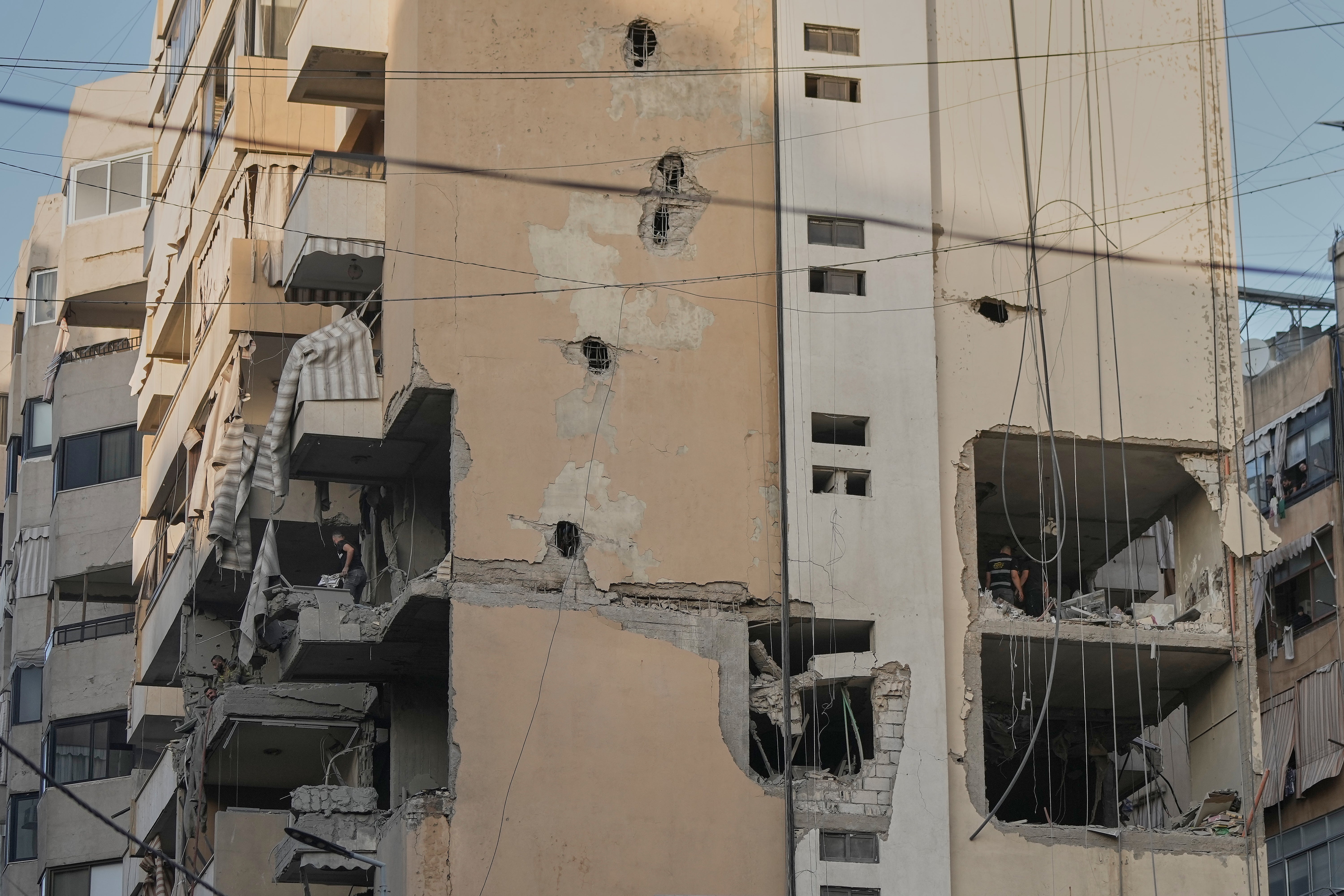 Civil defence workers inspect the damage after an apartment building is attacked by Israeli forces in southern Beirut