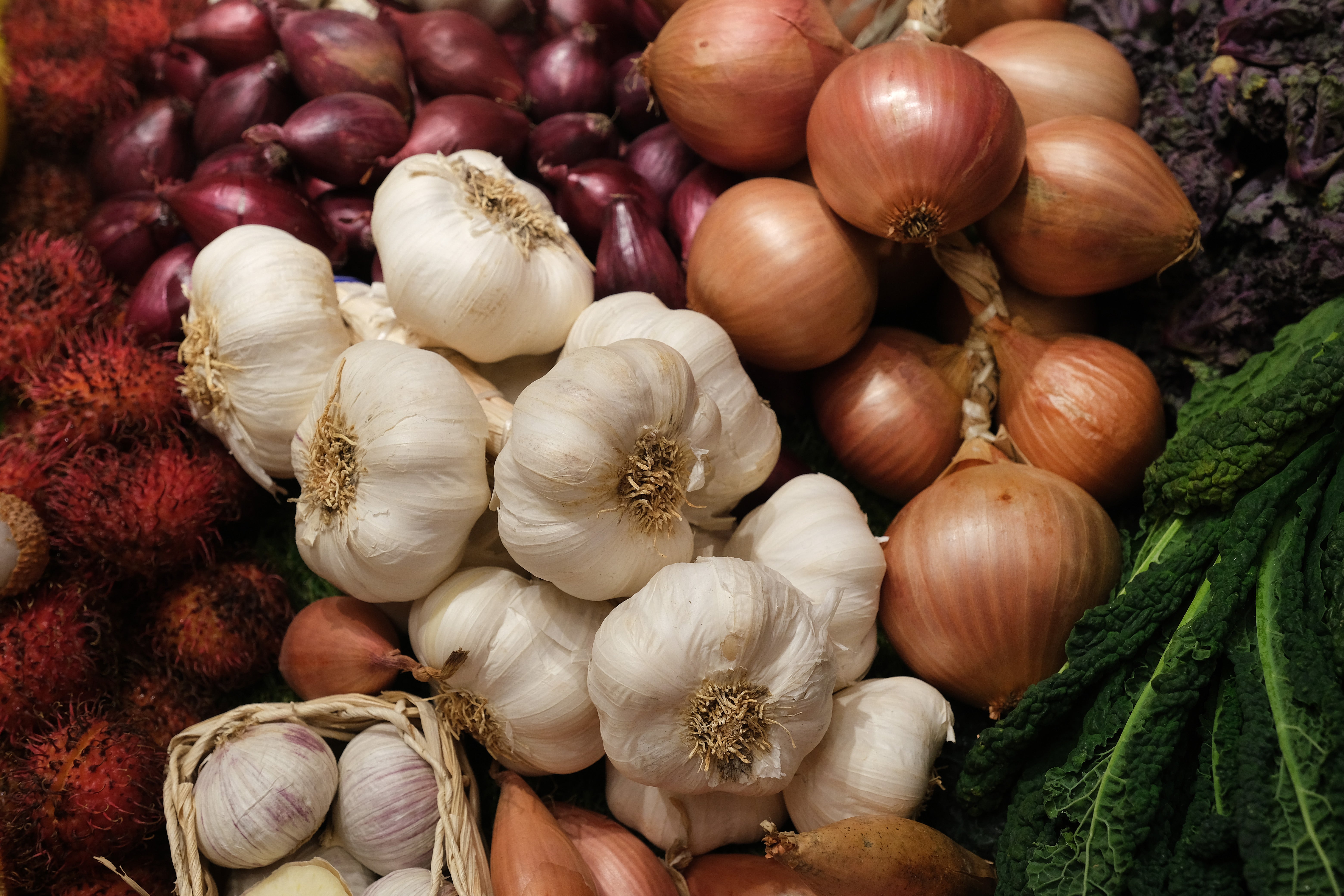 <p>Garlic, onions and shallots lie on display</p>