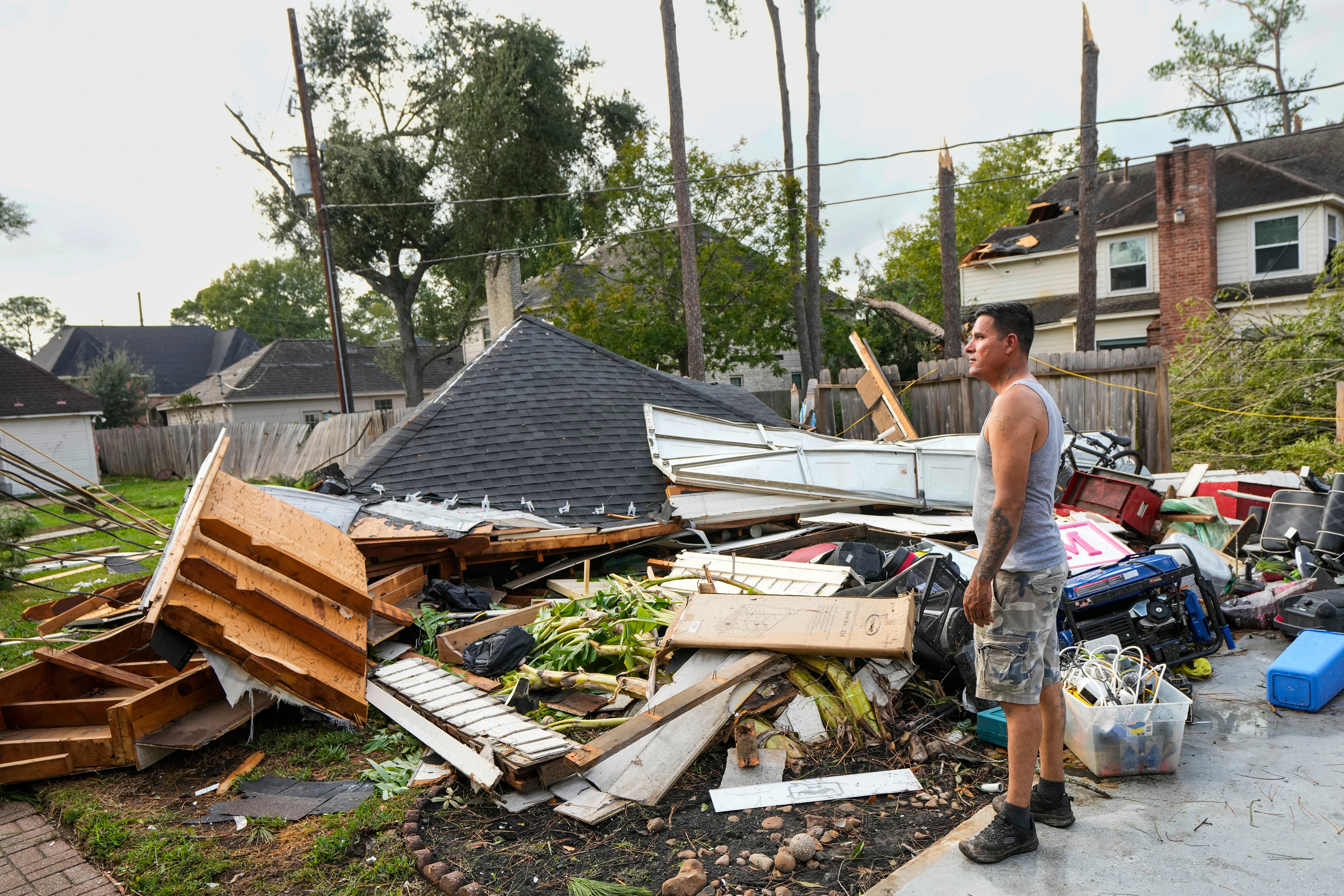 Jose Rosas surveys damage to Guillermo Vargas' home as while helping clean up storm damage in the Memorial Northwest subdivision, in Spring, Texas, Monday, Nov. 24, 2025