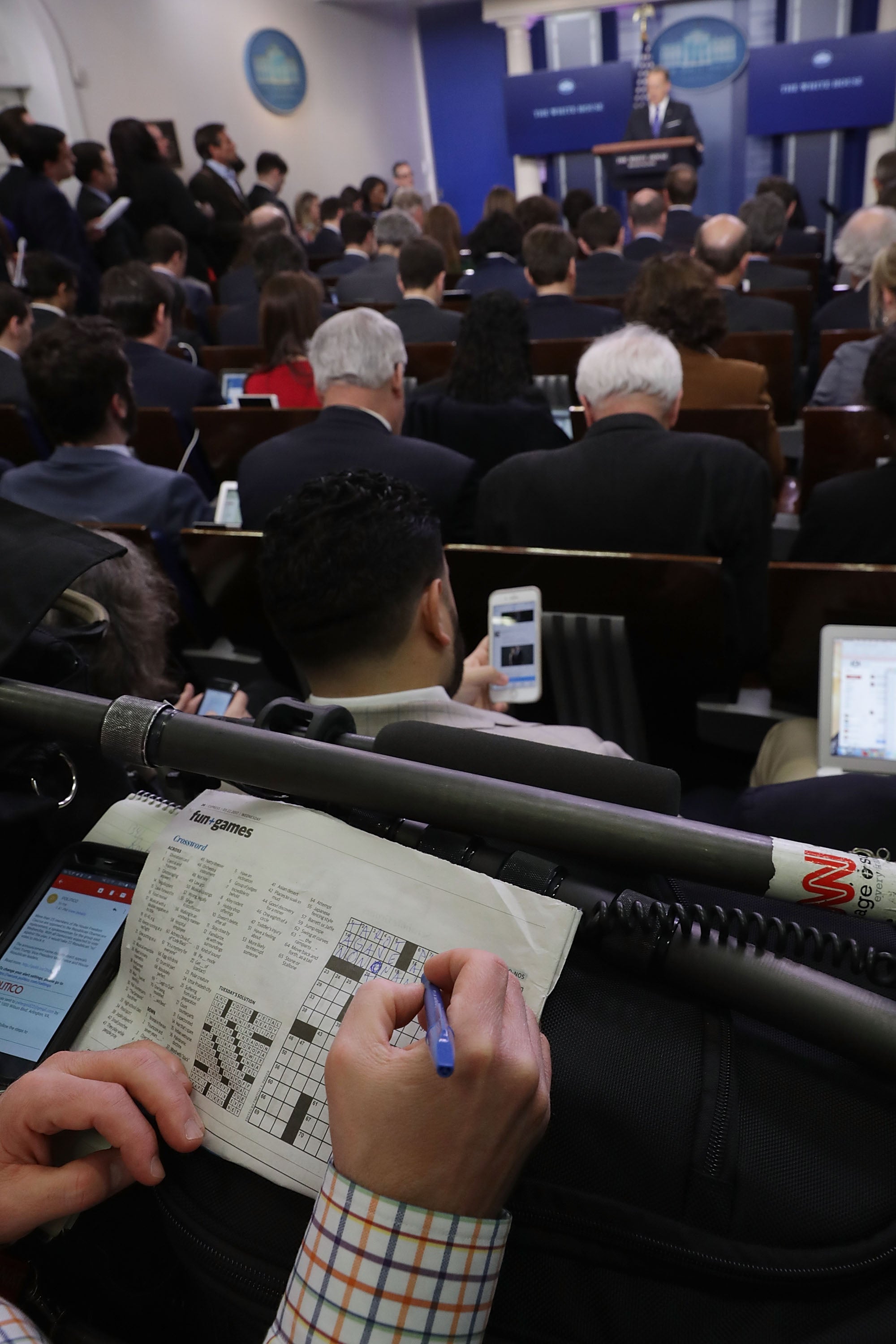 A journalist works on a crossword puzzle during a White House briefing in 2017