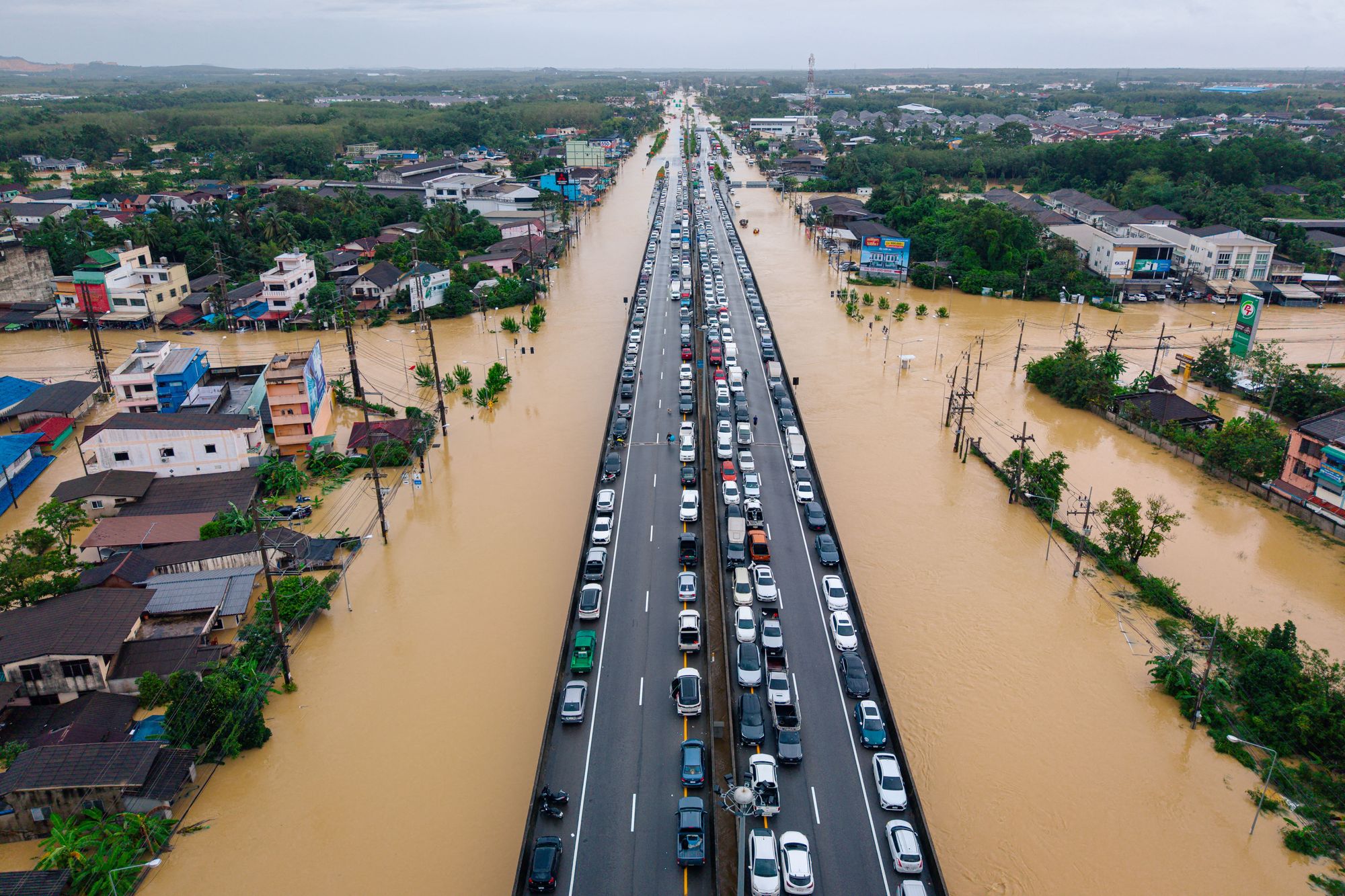 <p>Vehicles are parked on an elevated road to keep them out of floodwaters in Hat Yai, Songkhla province, Thailand</p>