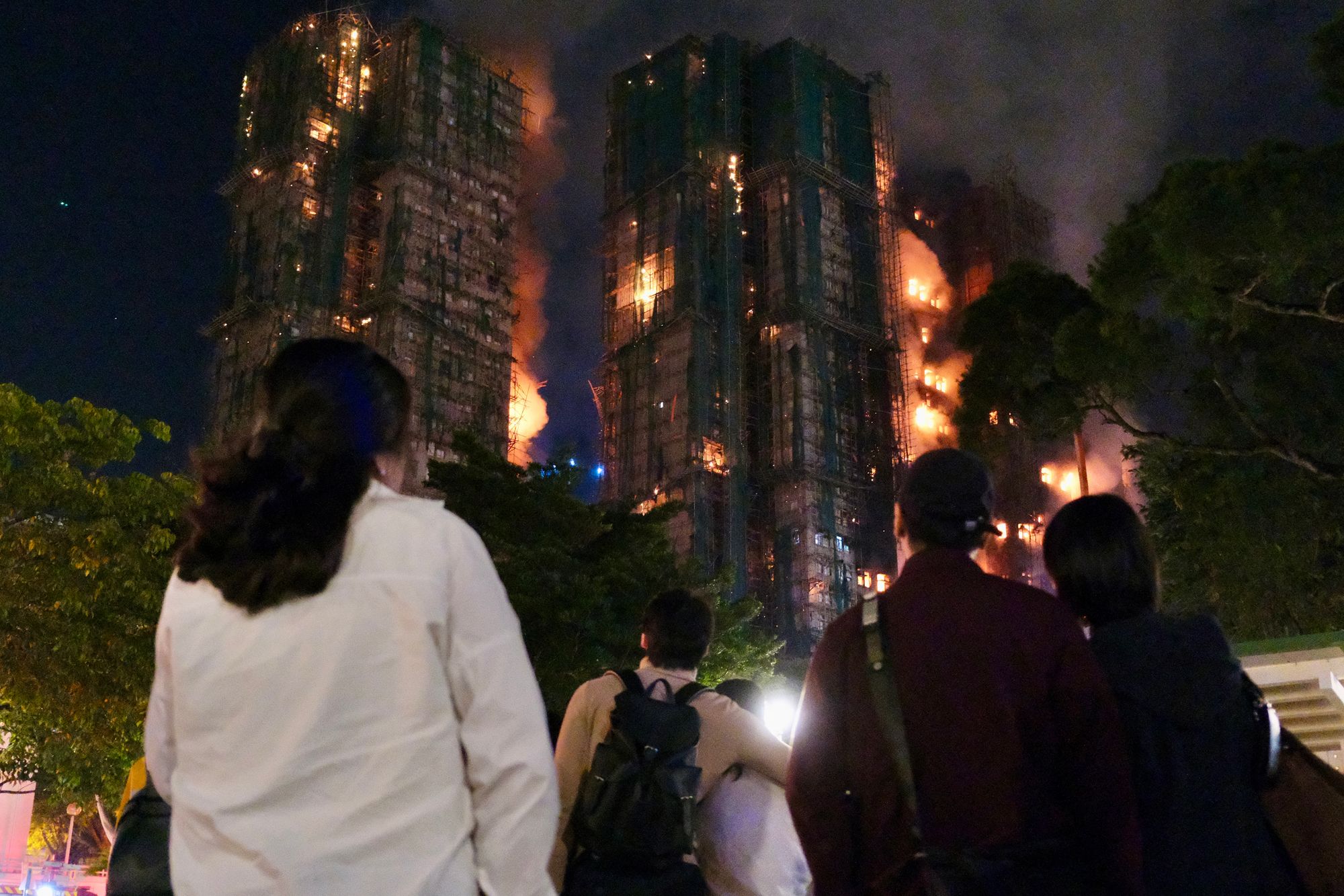 People look on as thick smoke and flames rise during a major fire at the Wang Fuk Court residential estate in Hong Kong's Tai Po district