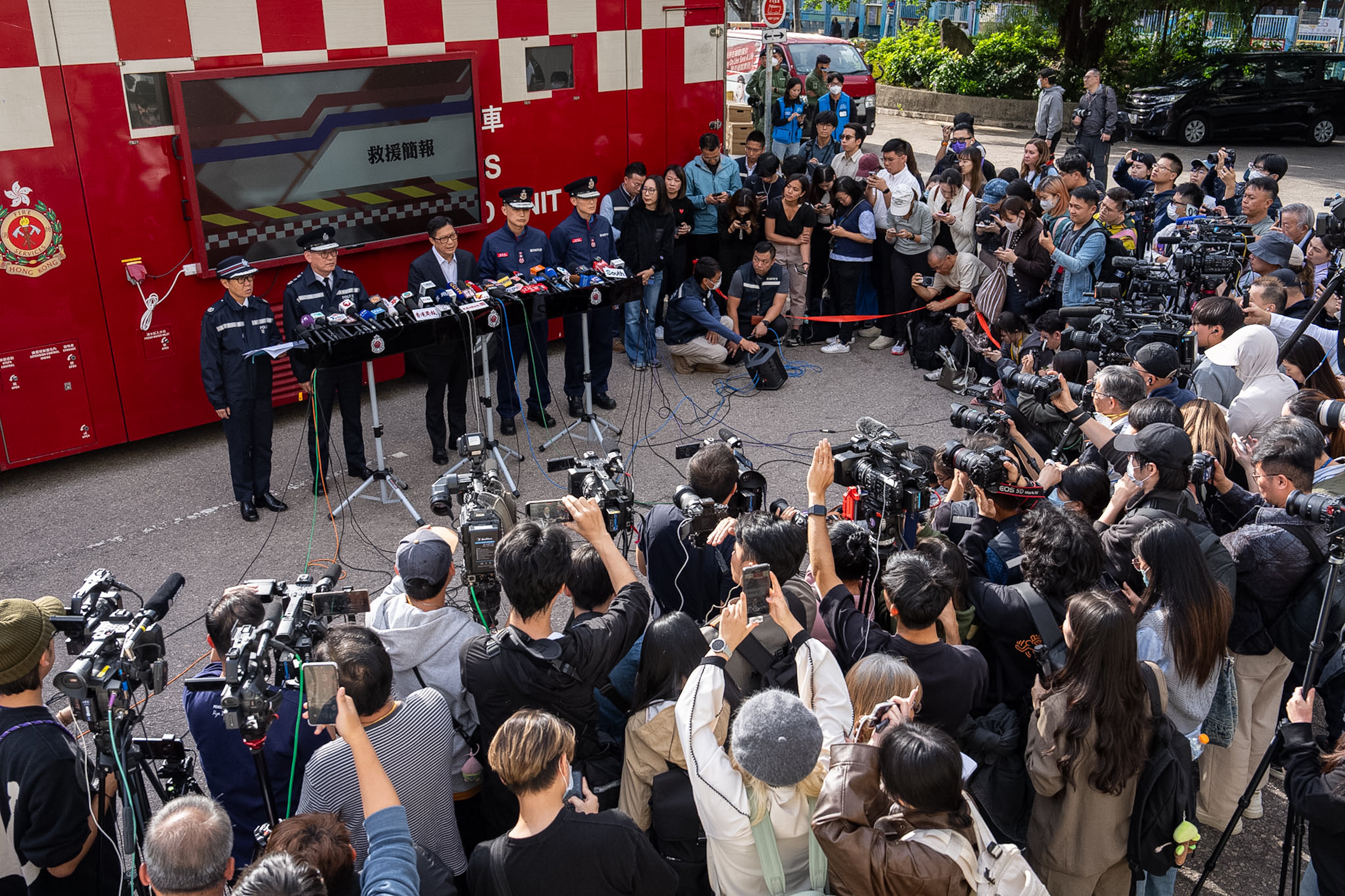 Hong Kong Secretary for Security Chris Tang, third from left at rear, speaks to the members of media after the deadly fires at Wang Fuk Court