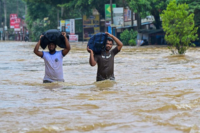 <p>People carrying belongings wade through a flooded road after heavy rainfall in Kaduwela on the outskirts of Colombo, Sri Lanka.</p>