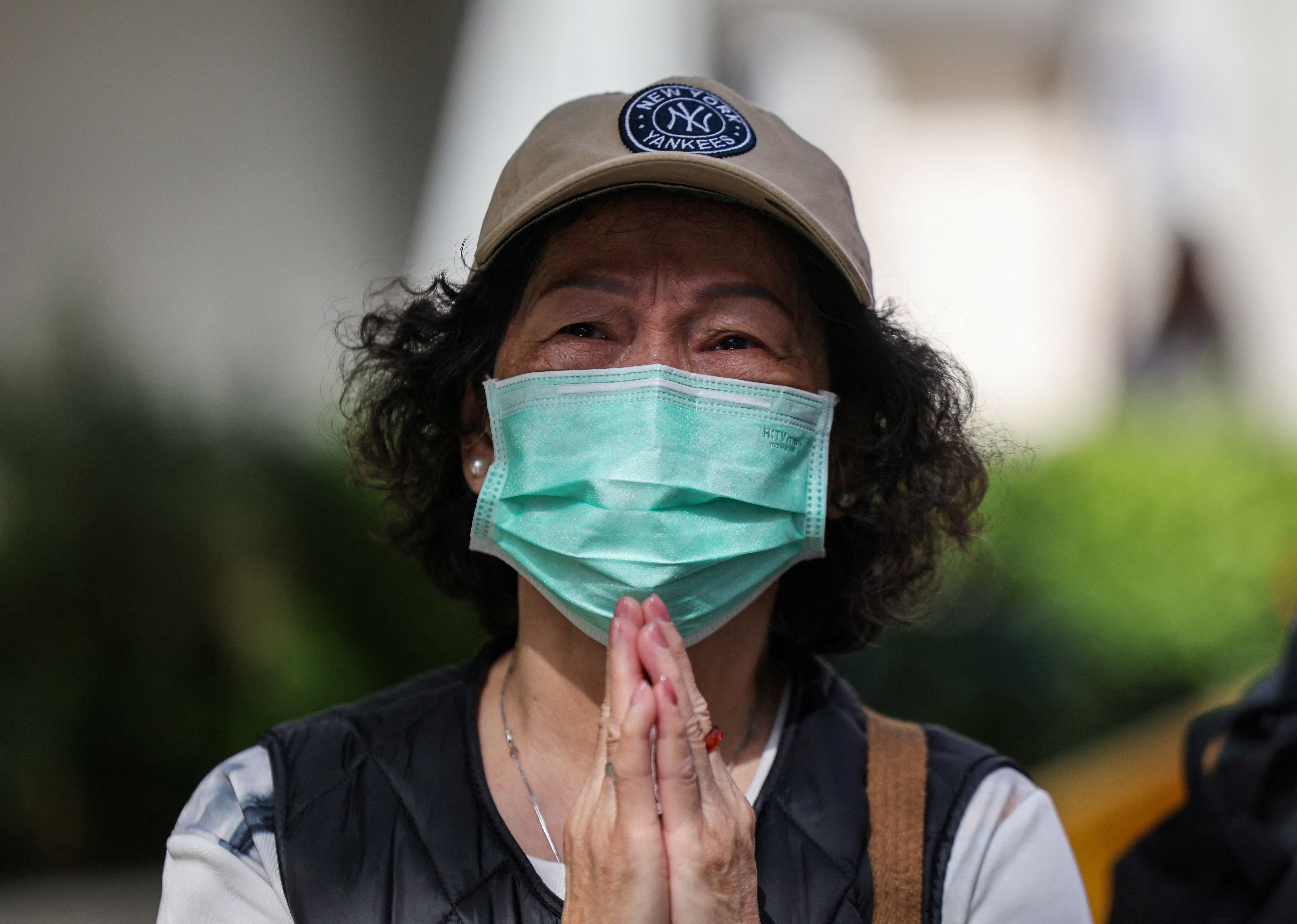 A woman in tears prays next to a local community centre after the deadly fire at the Wang Fuk Court housing complex, in Tai Po, Hong Kong, China
