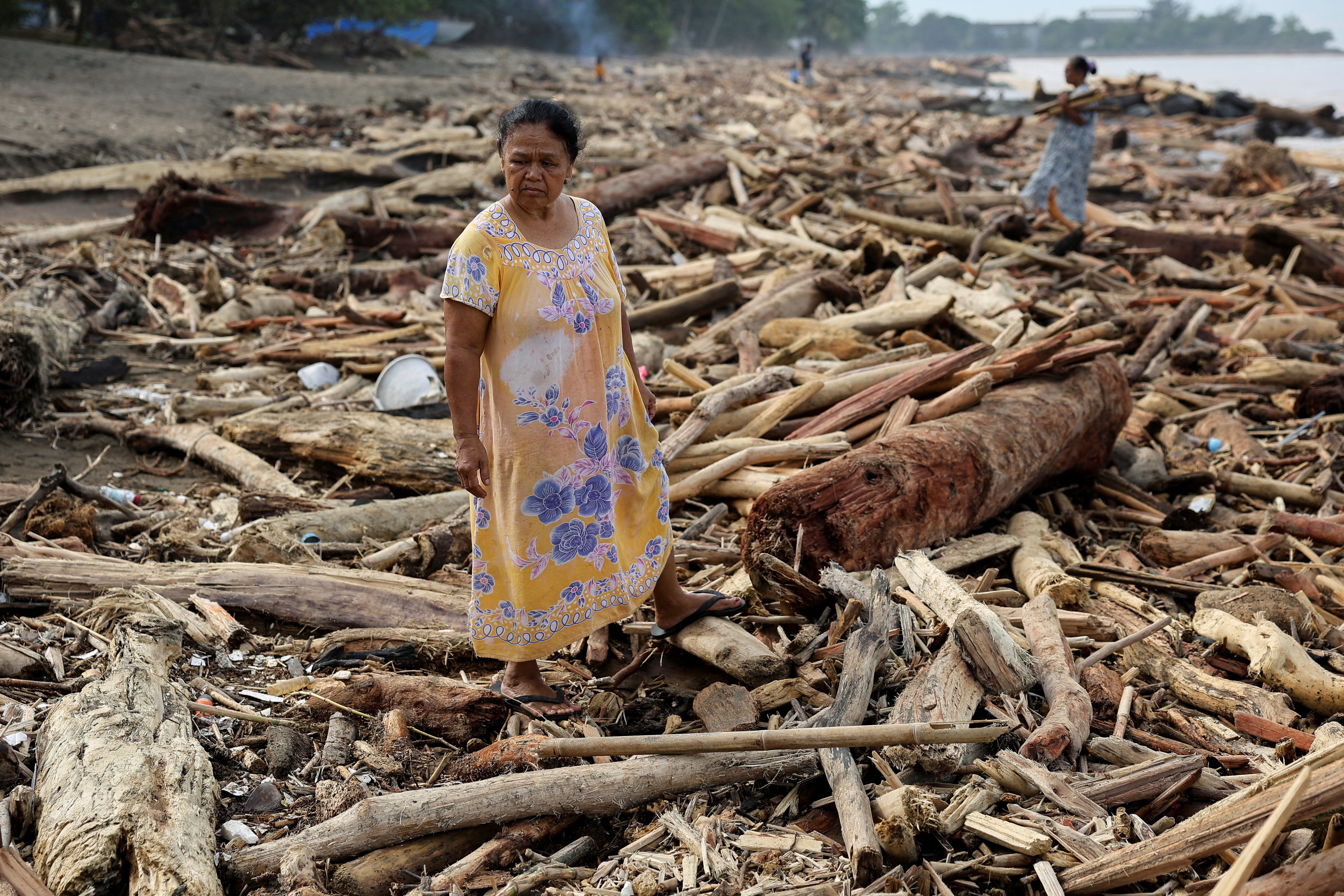 A woman stands on shore after deadly flash floods in Padang, West Sumatra, Indonesia