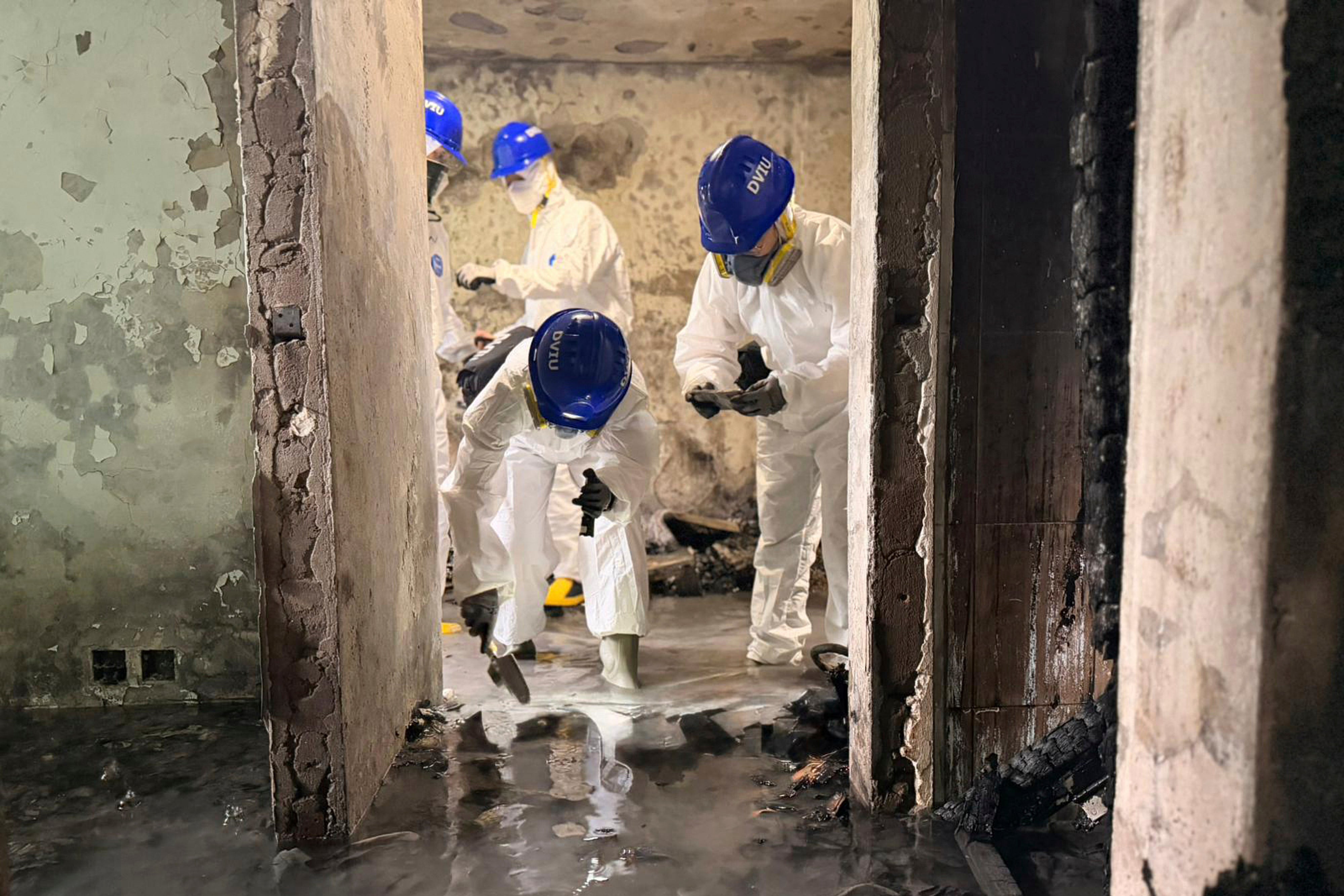 Members of the Disaster Victim Identification Unit work in an apartment in the aftermath of the Wang Fuk Court fire in the Tai Po district of Hong Kong on 30 November 2025