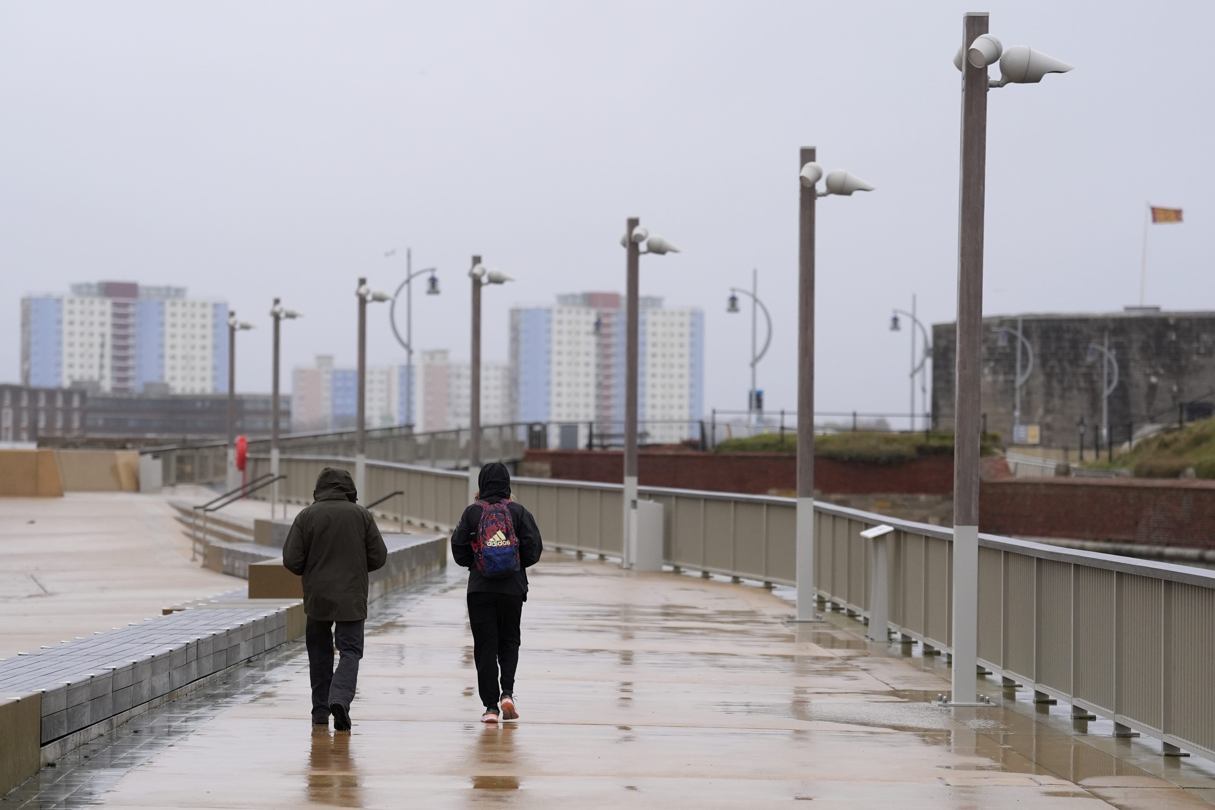 People wearing coats and hoods walking along the wet sea front near to Old Portsmouth in Hampshire (Andrew Matthews/PA)