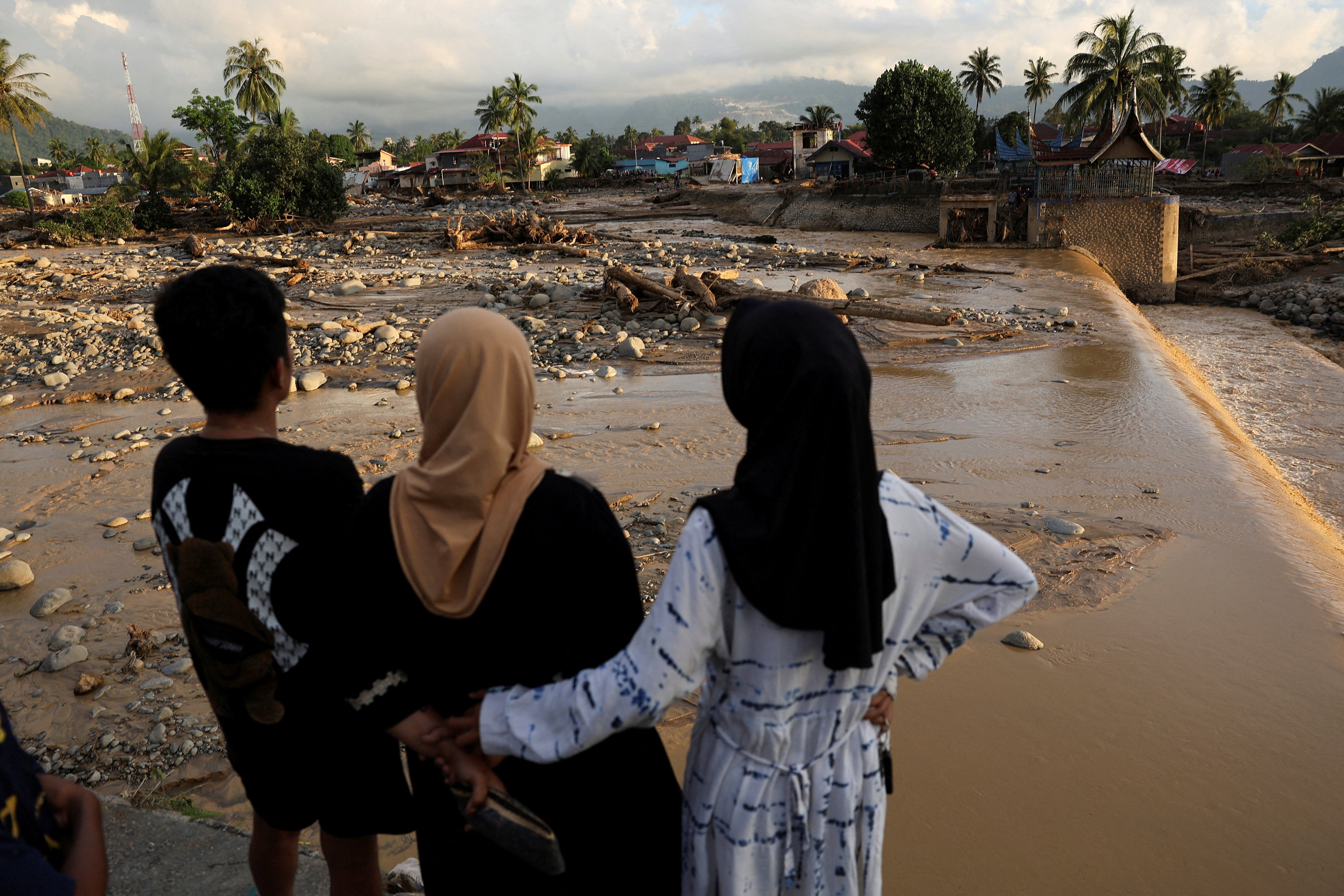 Local residents observe an area hit by deadly flash floods following heavy rains in Padang, West Sumatra province