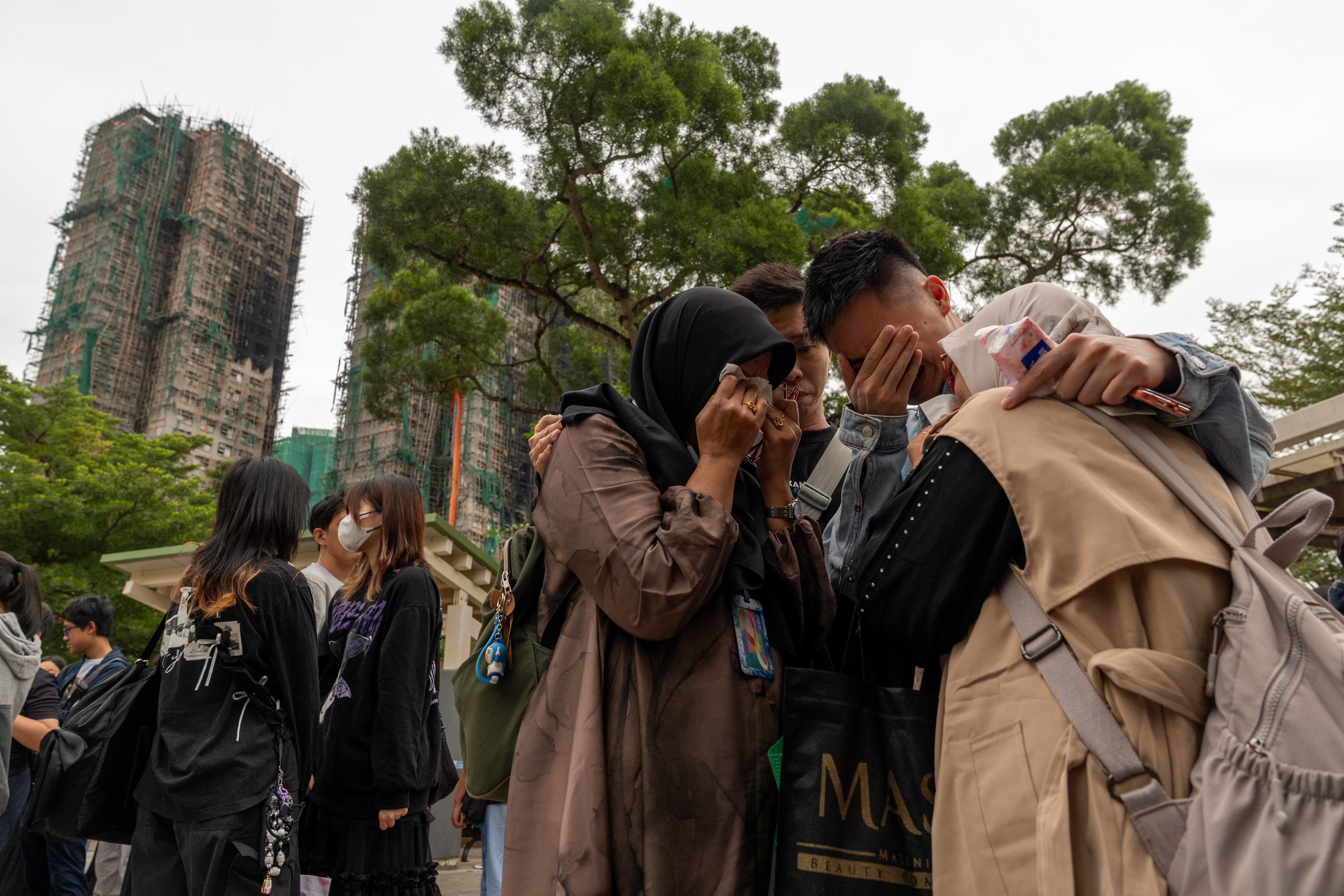 People react after a fire breaks out at the Wang Fuk Court