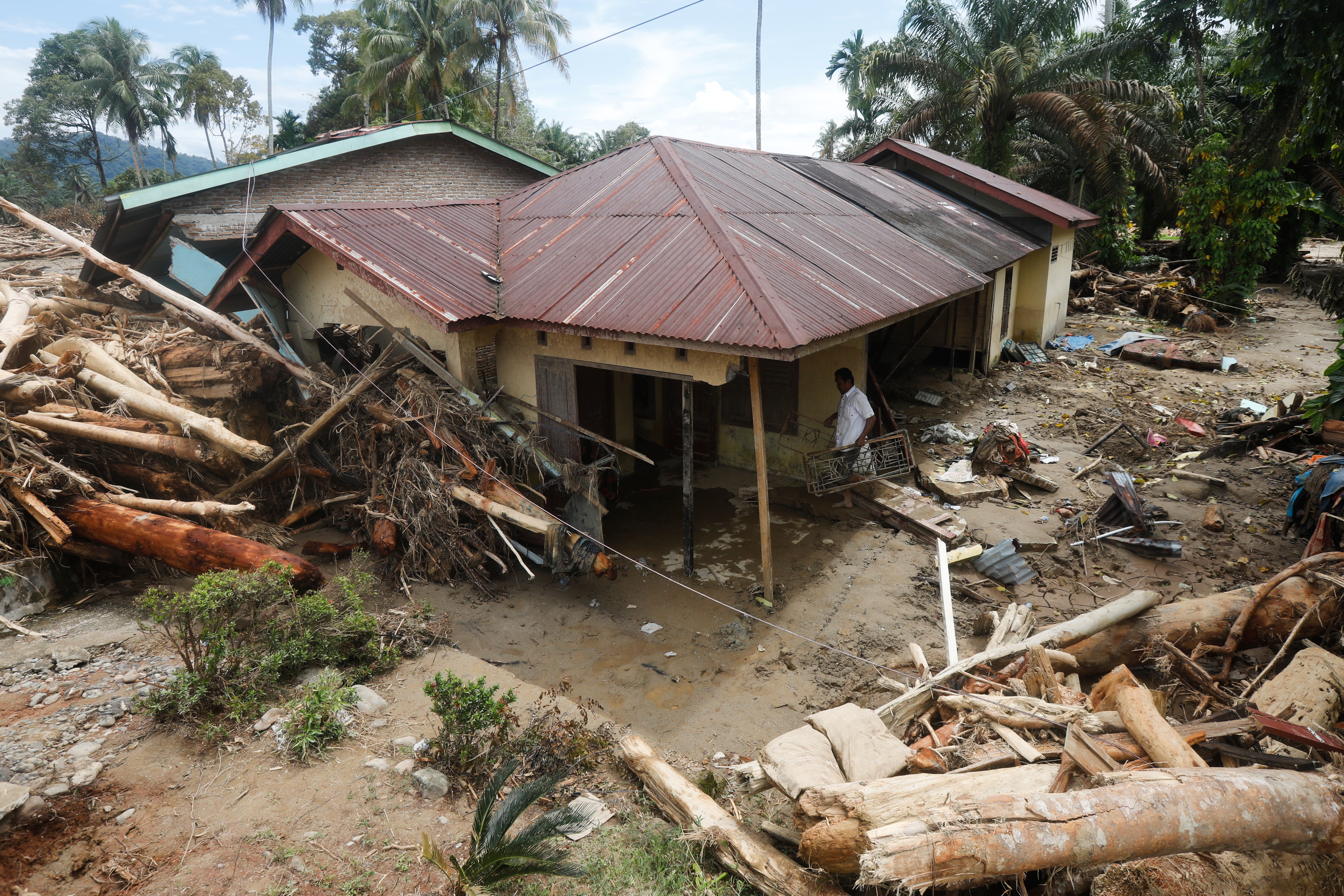 A man cleans his house at a village affected by flood in Batang Toru, North Sumatra, Indonesia