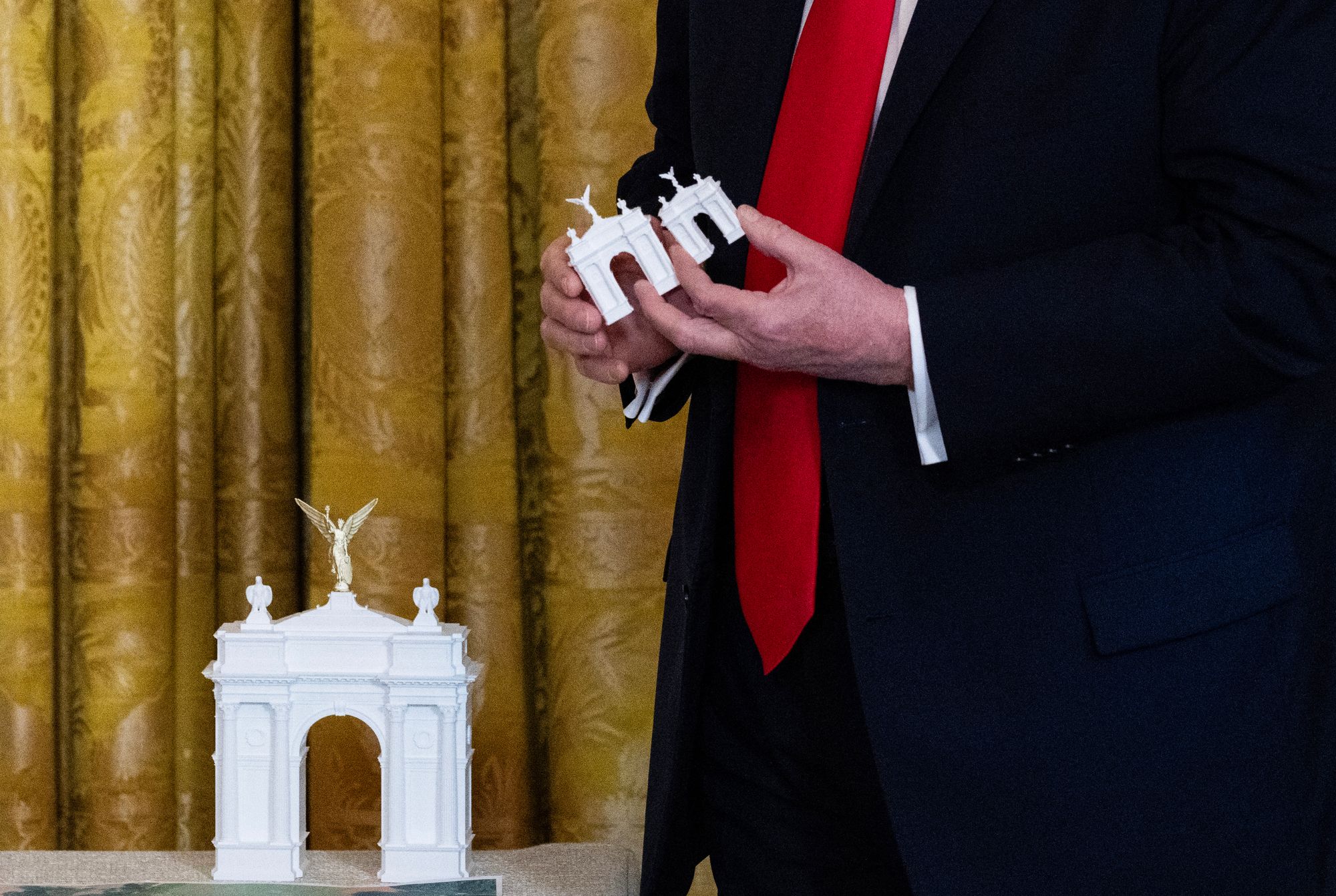 Trump holds models for a proposed Independence Arch as he speaks during a dinner with ballroom donors in the East Room of the White House in Washington, DC on October 15, 2025