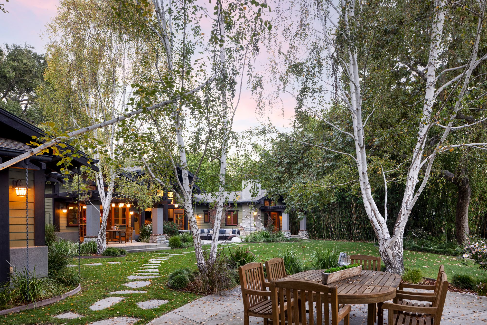 The home has a private 30-foot dock with 80-foot frontage, sweeping lawn, and multiple outdoor terraces framed by trees