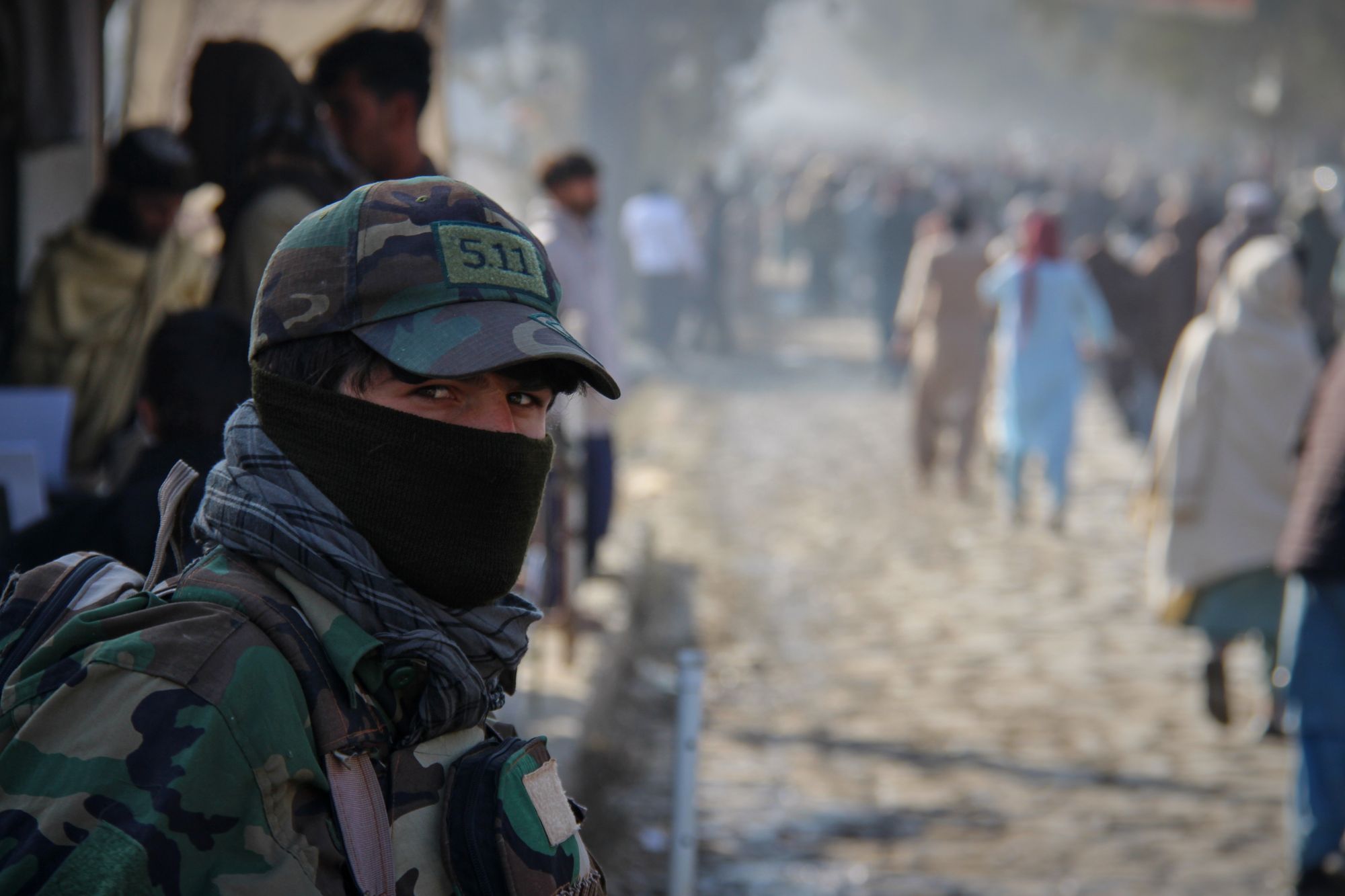 A Taliban policeman looks on as a crowd heads toward the stadium to witness the execution