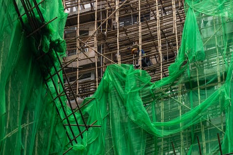 <p>Construction workers remove scaffolding nets from a renovation project after the deadly fire</p>