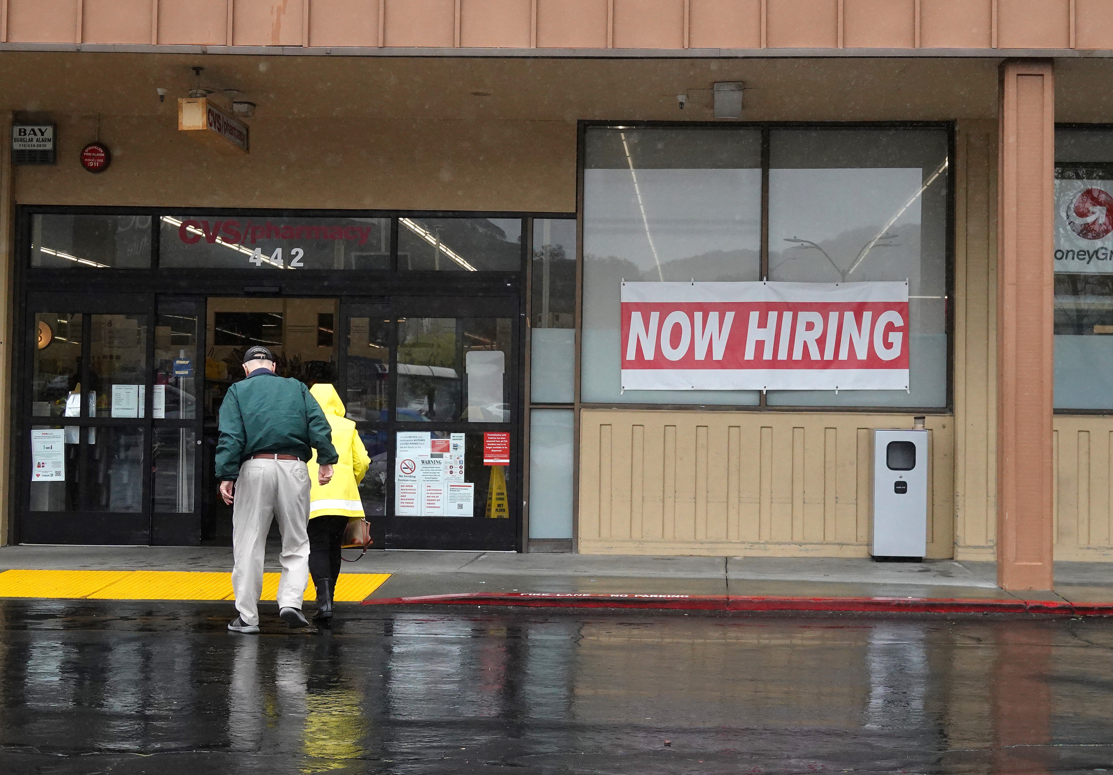 People walk by a now hiring sign posted in front of a CVS store on April 07, 2023 in San Rafael, California