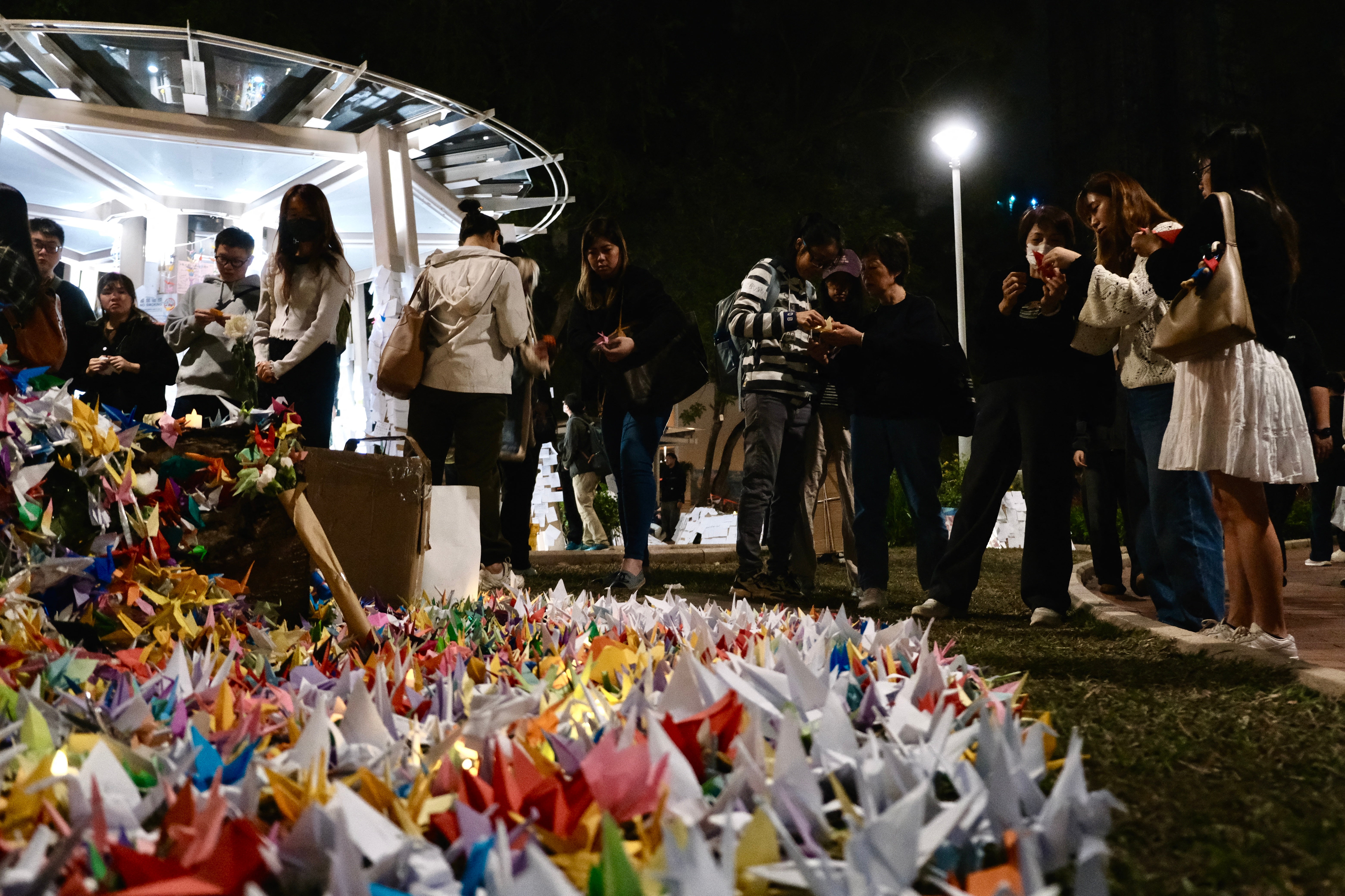 <p>Mourners fold paper cranes during a vigil held outside the Wang Fuk Court apartment blocks in the aftermath of the deadly 26 November fire in Hong Kong’s Tai Po district on 3 December 2025. - The death toll from Hong Kong’s worst fire in decades rose to 159 after all affected housing blocks were searched, police said on 3 December, cautioning that the figure may not be final</p>