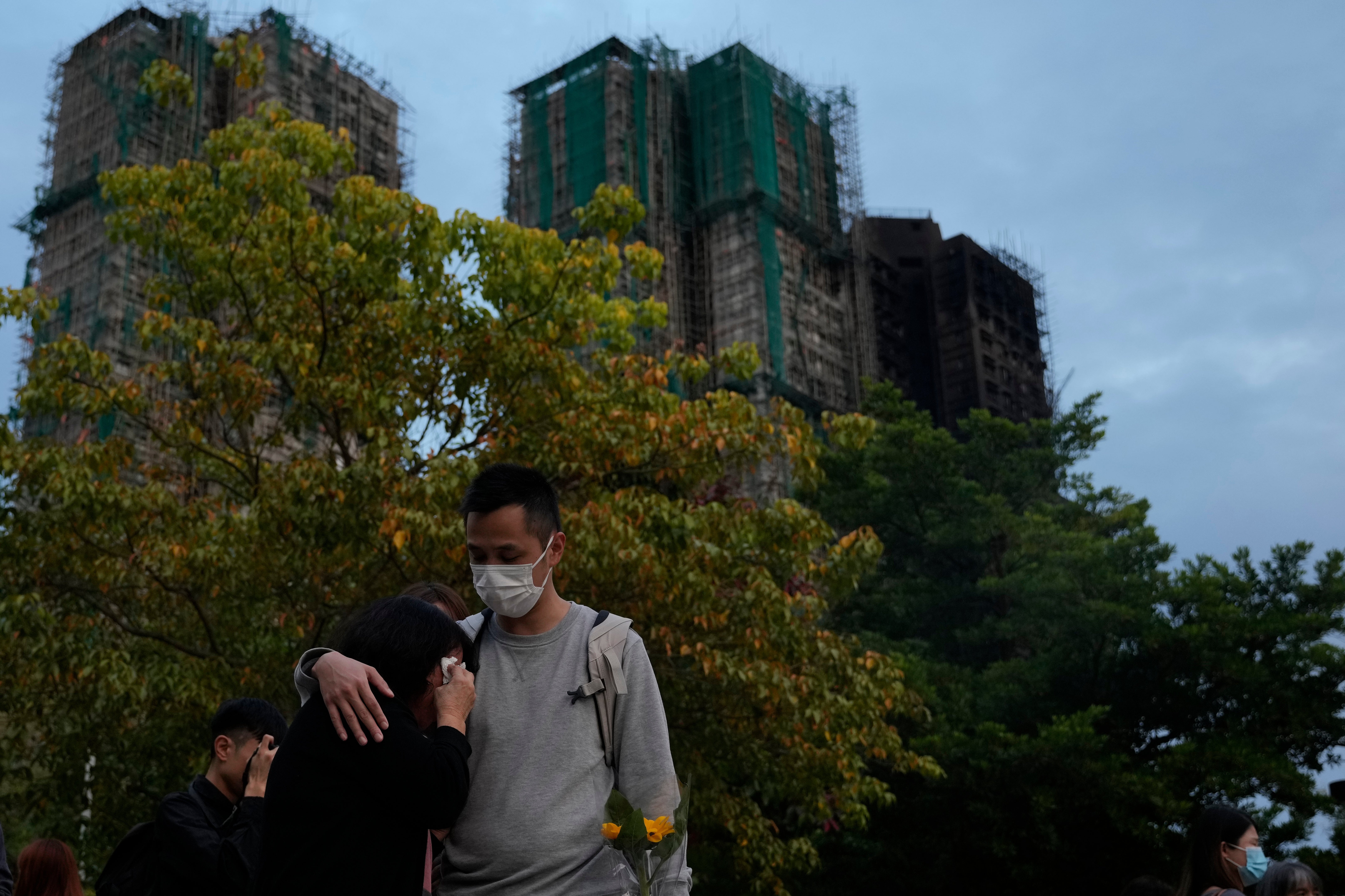 <p>A man consoles a woman near the Wang Fuk Court complex in Hong Kong on 2 December 2025</p>