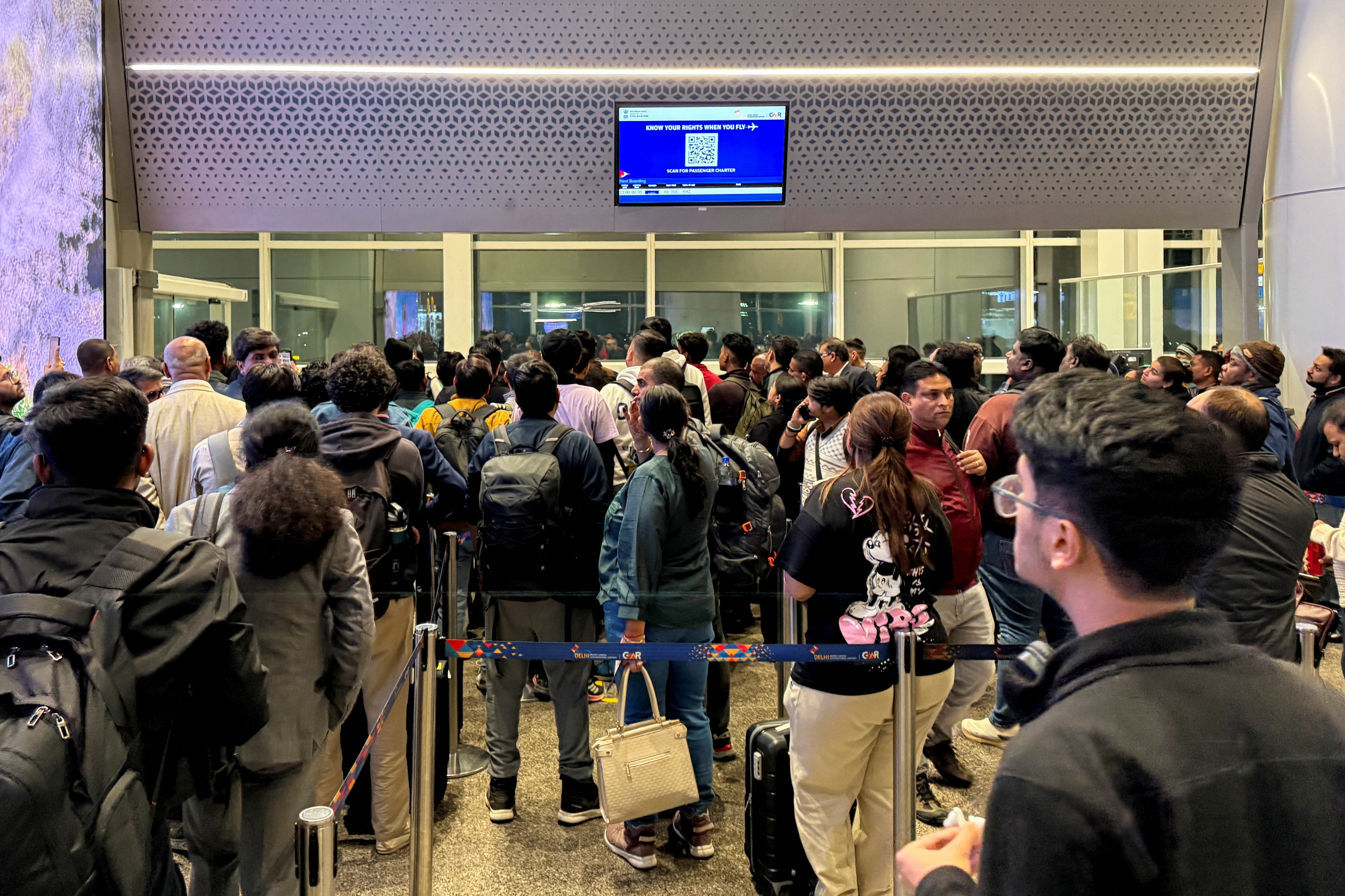 Passengers crowd outside a boarding gate as they wait to take a delayed IndiGo flight at the Indira Gandhi international airport in Delhi
