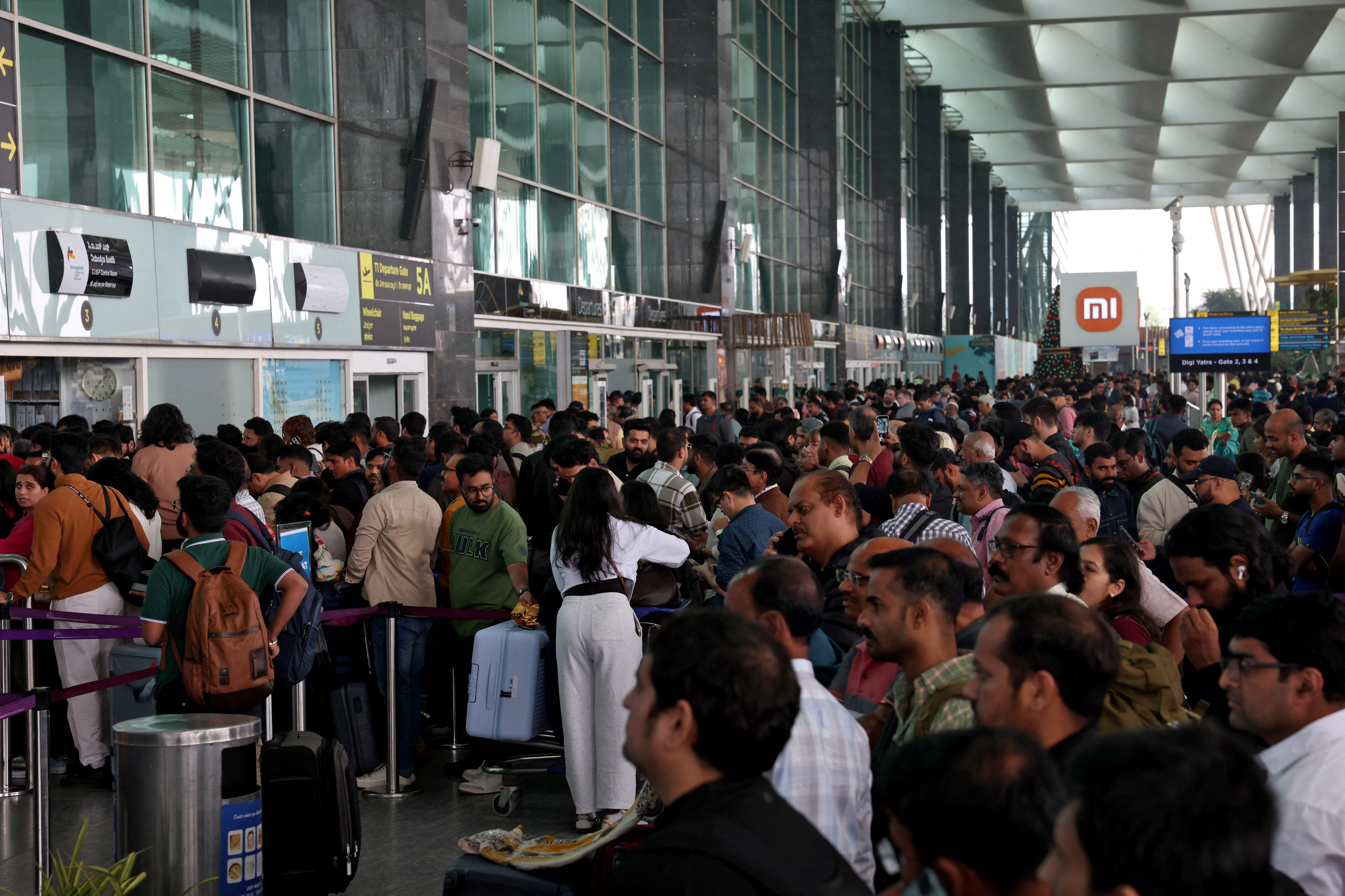 Travellers wait in queues at IndiGo ticketing kiosks to check at the Bengaluru airport