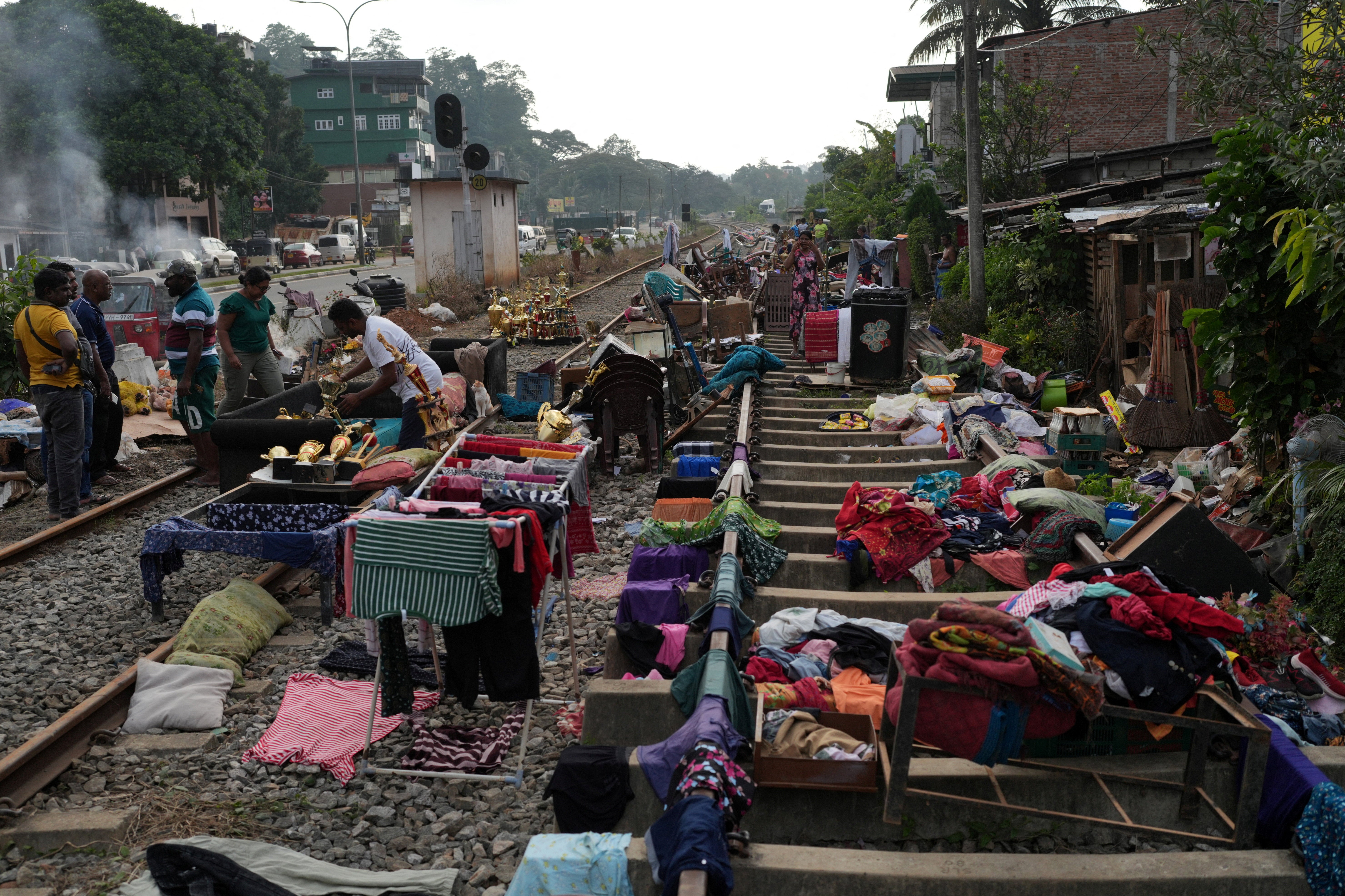 People affected by floods collect their belongings from the railway tracks after drying them following Cyclone Ditwah, in Kandy, Sri Lanka