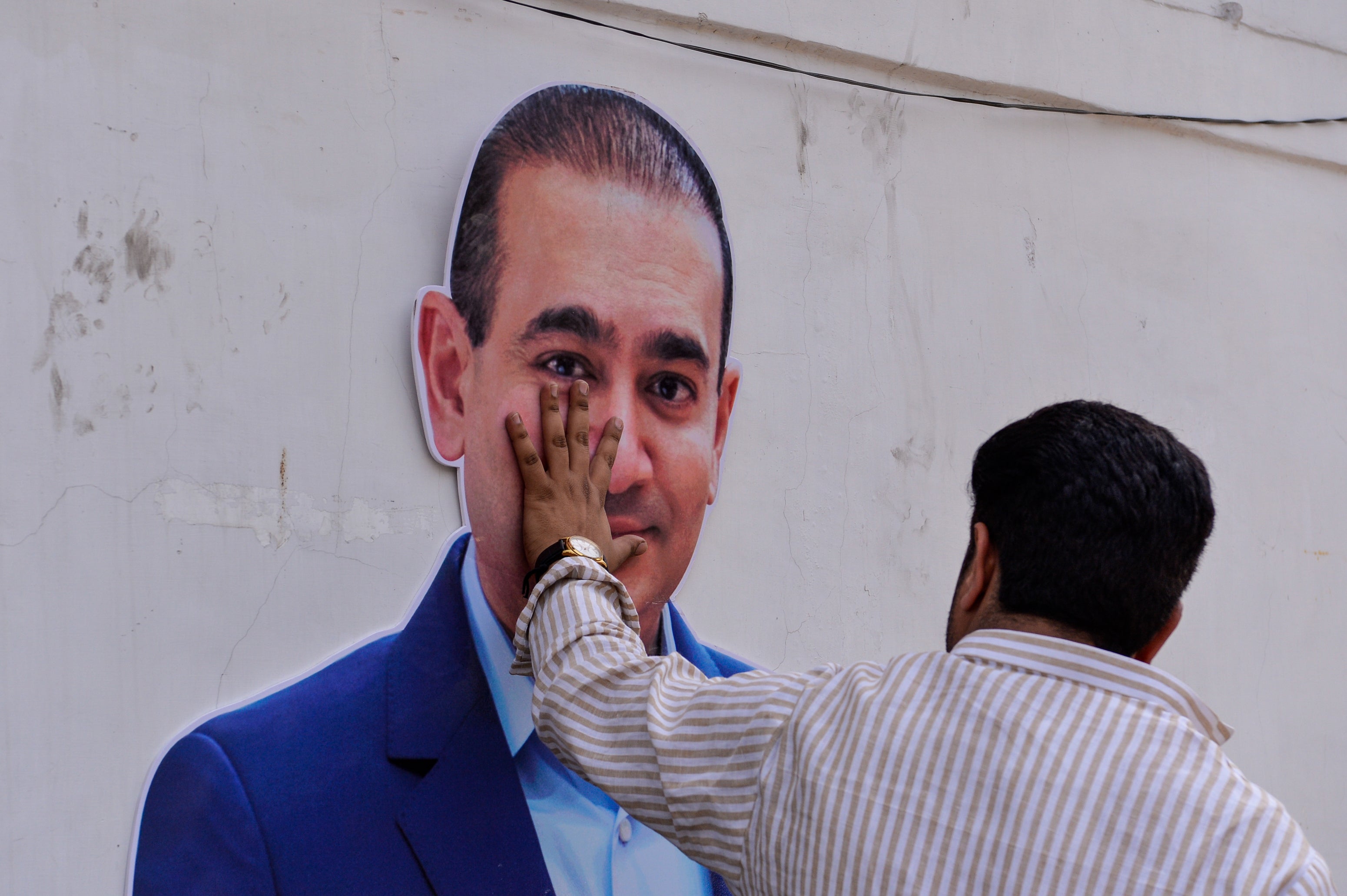 An Indian protester touches a cutout of billionaire jeweller Nirav Modi during a demonstration in New Delhi in 2018