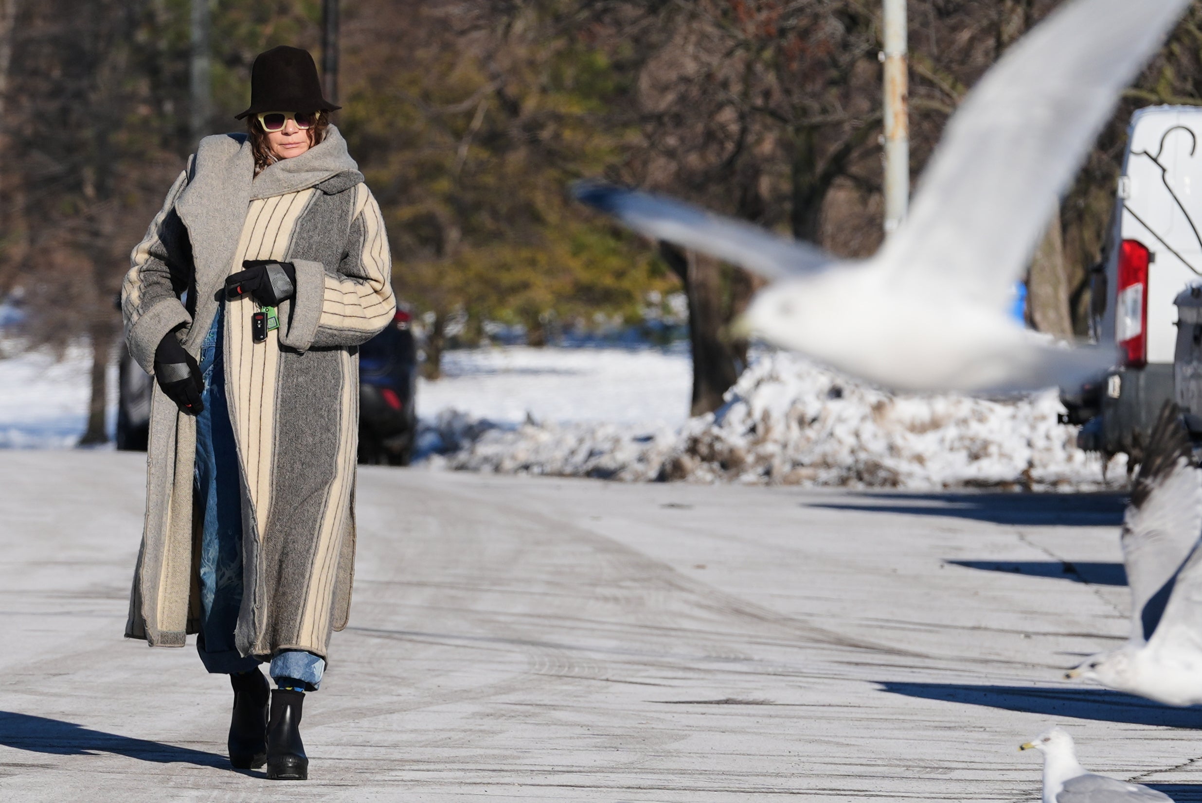 A woman bundles up as she takes a walk during a cold weather day in the snow-covered at Lake Michigan, in Chicago, Thursday, Dec. 4, 2025