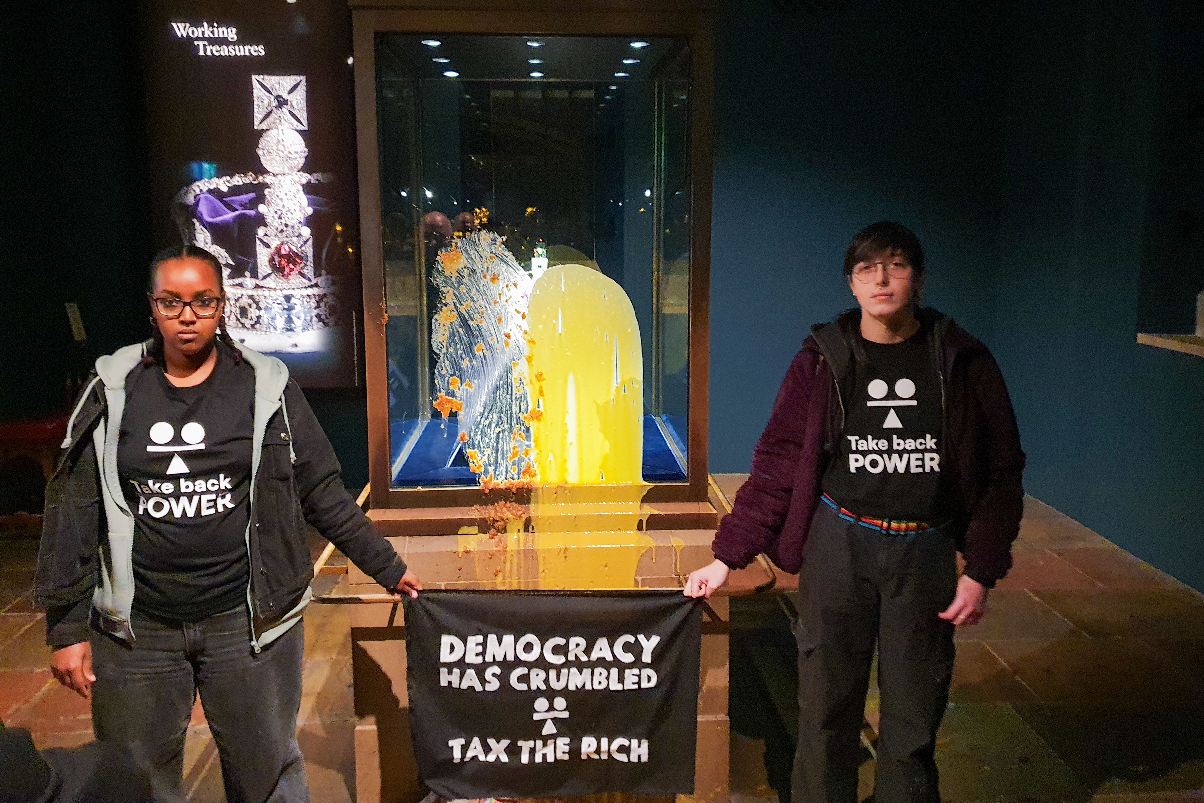 Protesters standing next to the defaced Crown Jewels case on Saturday morning (Take Back Power/PA)