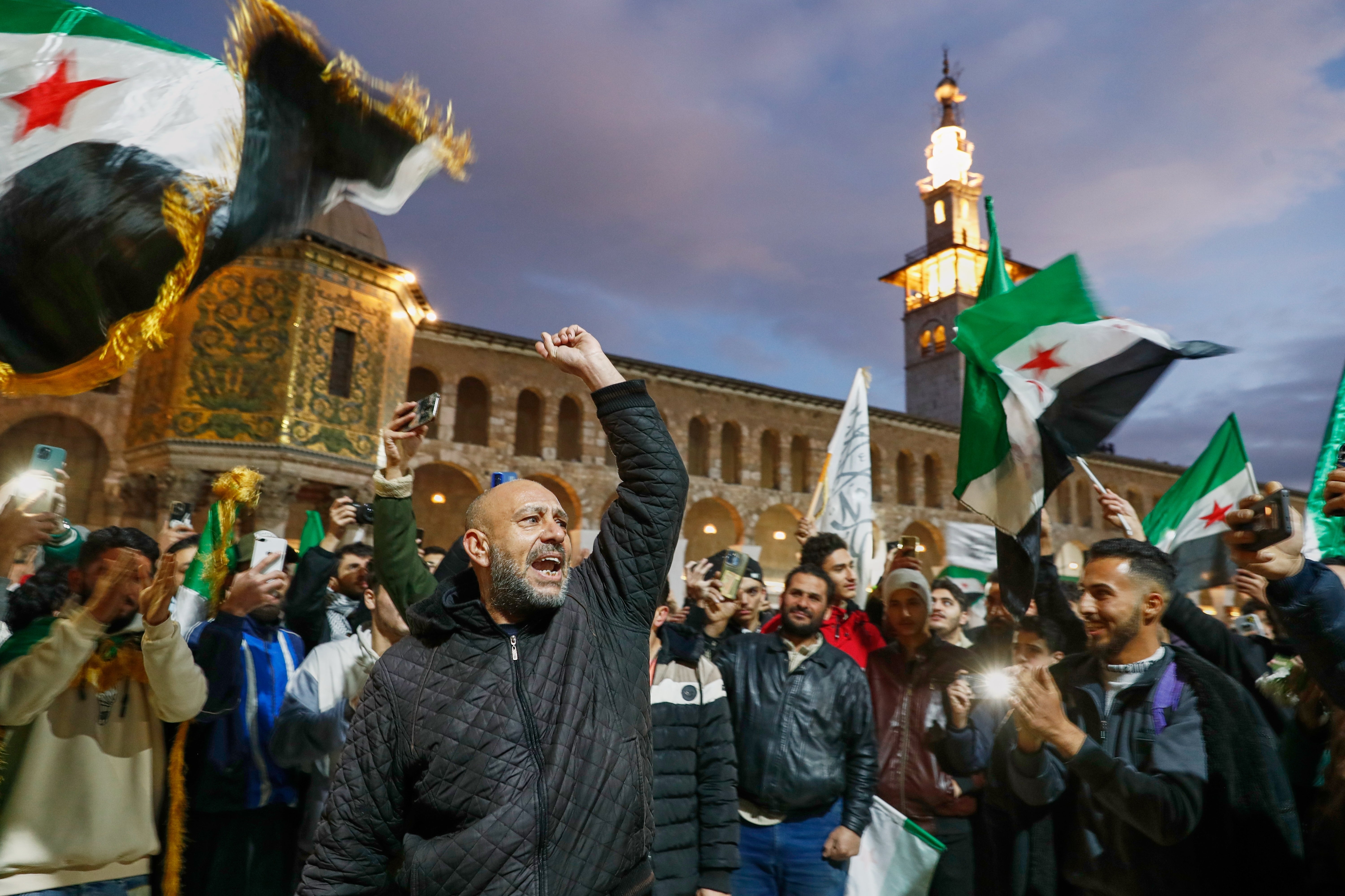 <p>Syrians shout slogans and wave flags outside the Umayyad Mosque before a prayer held ahead of celebrations marking the first anniversary of Assad’s ousting</p>