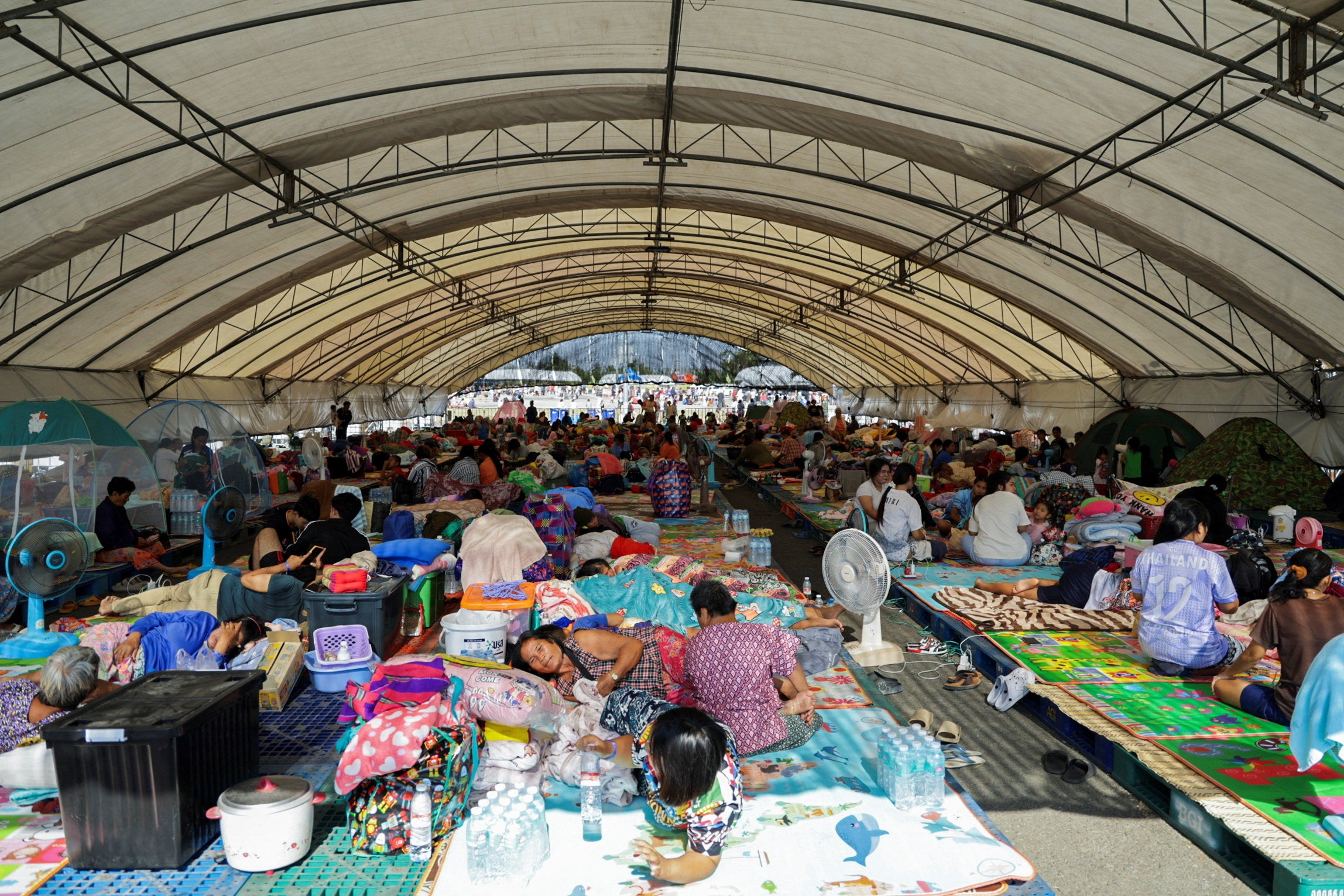 People rest at a shelter, following fresh military clashes between Thailand and Cambodia along parts of their disputed border, in Buriram province