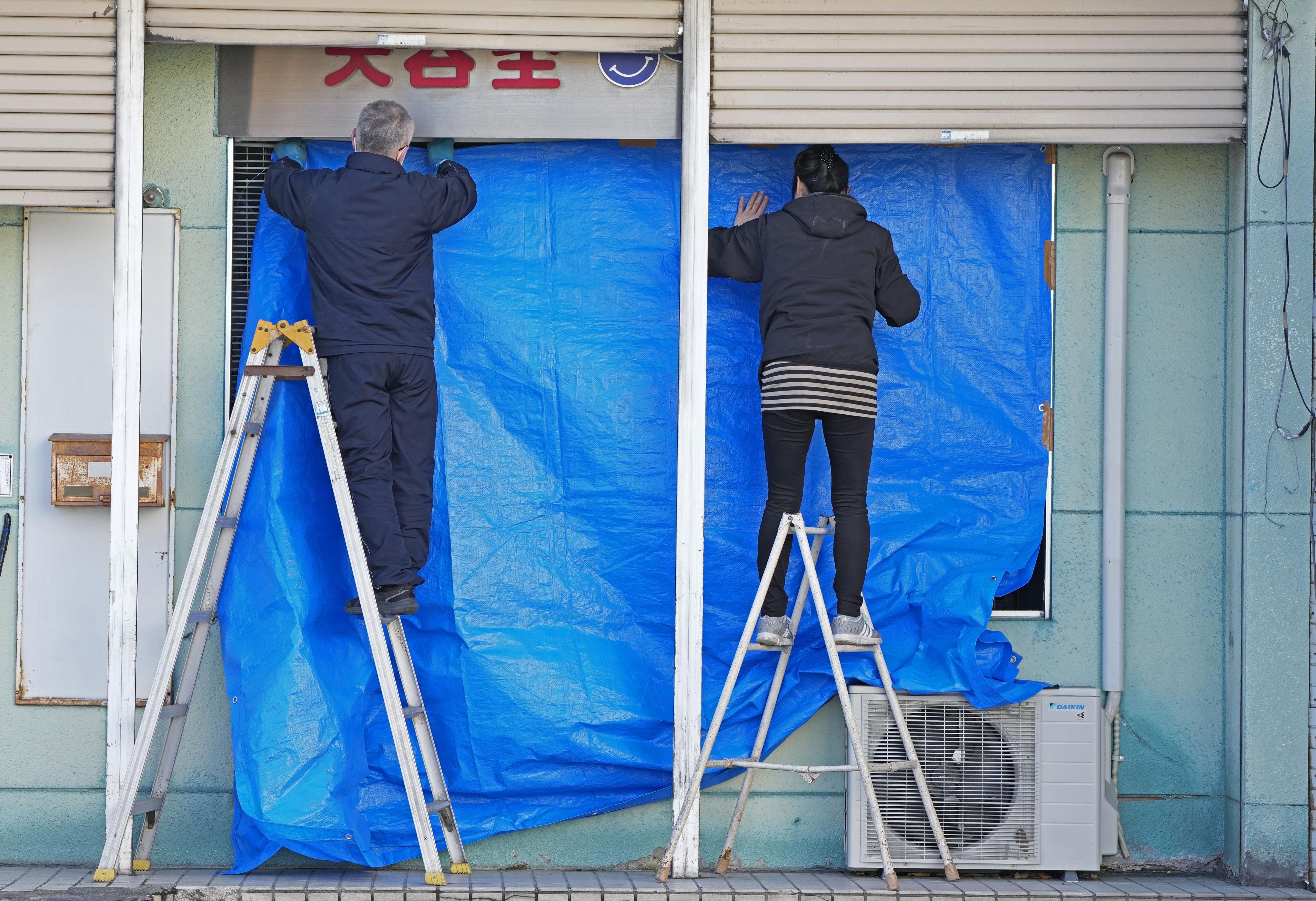 People cover the broken glasses with a blue sheet at a beauty salon in Hachinohe, Aomori prefecture, northern Japan Tuesday, 9 December 2025, following a powerful earthquake on late Monday