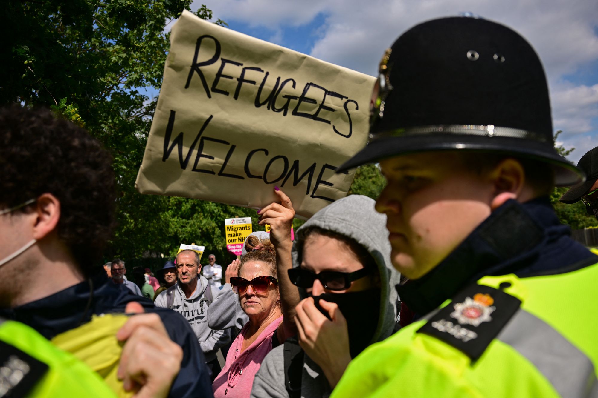 A demonstrator holds a placard reading 'Refugees Welcome' during a counter protest to an anti-immigration protest outside the Sheraton Four Points hotel, believed to be housing asylum seekers, in Horley, south of London, on August 23, 2025. A total of 111,084 people applied for asylum in the UK in the year to June 2025 -- the highest number ever.