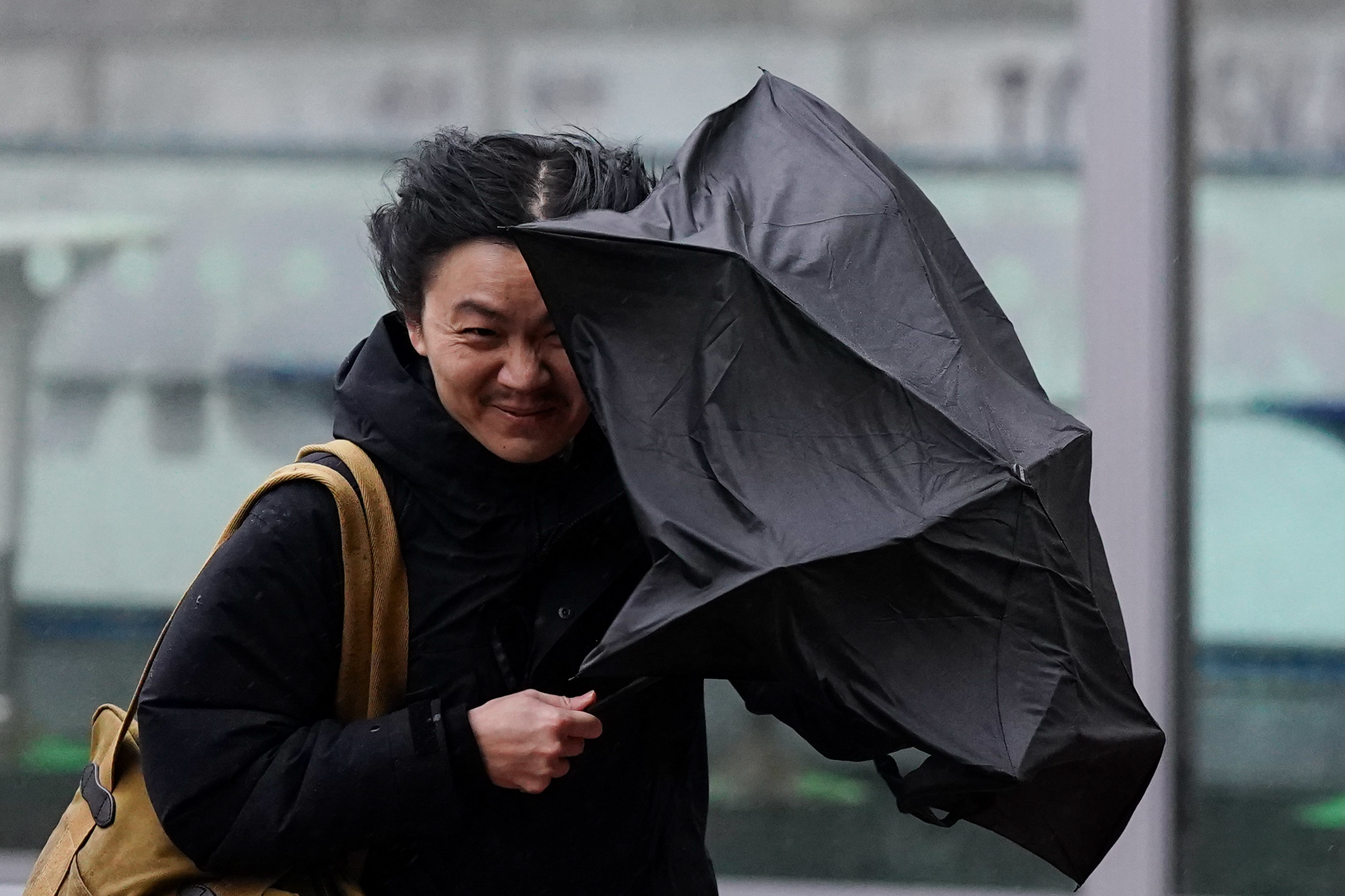 A person struggles to hold on to their umbrella during strong wind in Birmingham (Jacob King/PA)