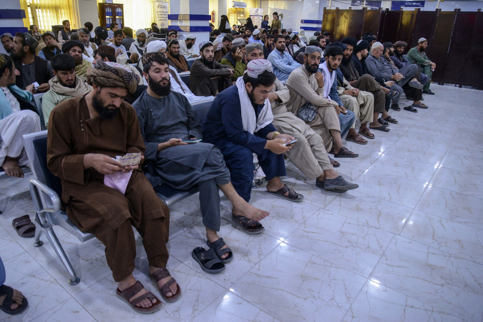 File: Afghan men wait to withdraw money inside a bank in Kandahar