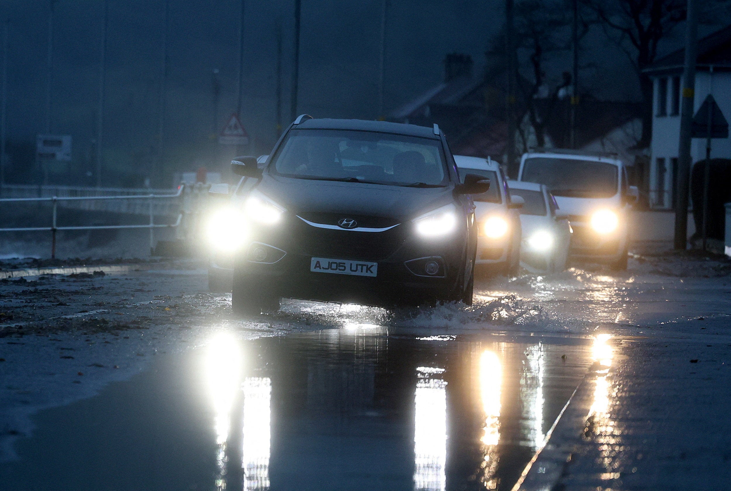 Vehicles drive along a flooded coastal road in Northern Ireland, United Kingdom