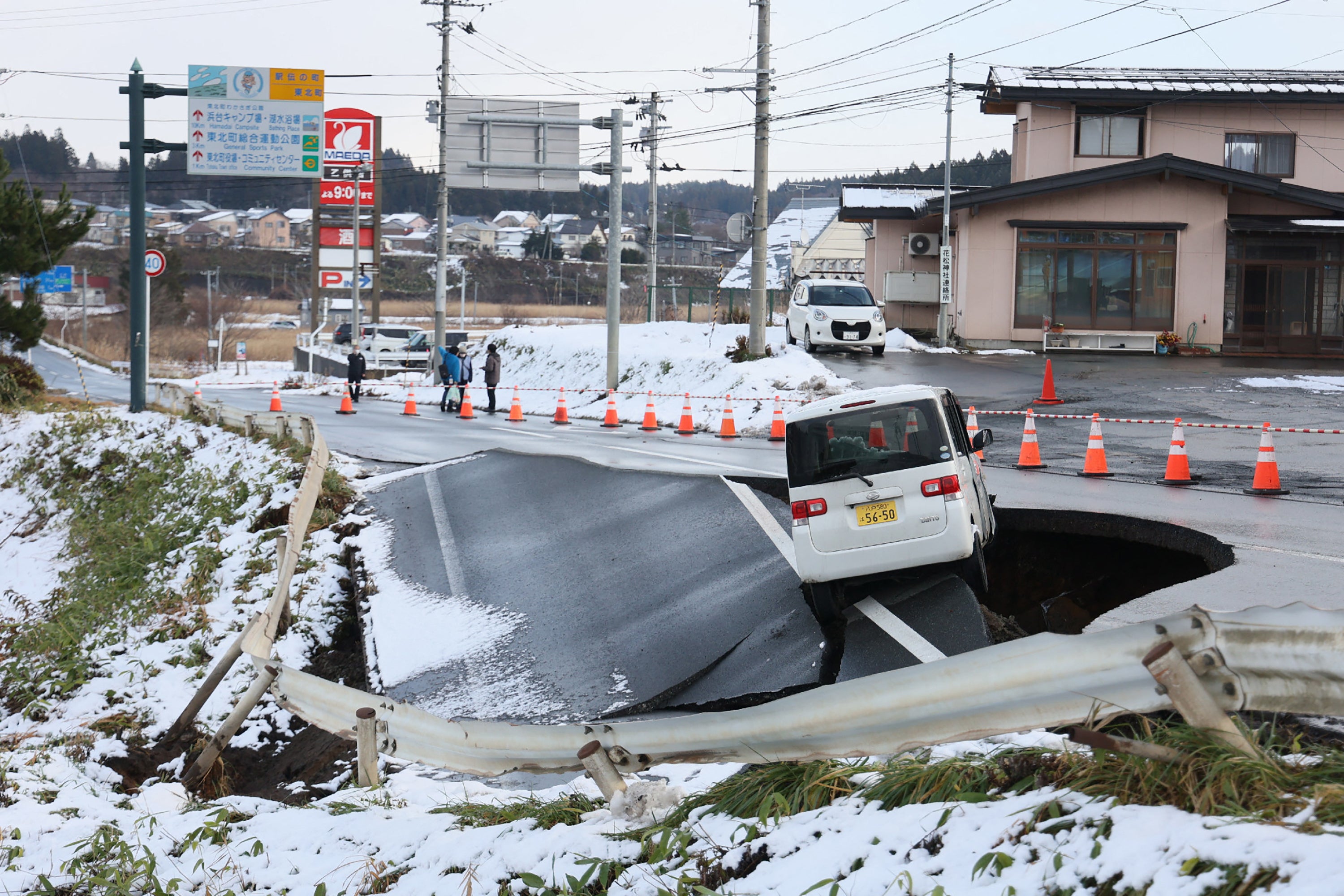 A vehicle rests on the edge of a collapsed road in Tohoku town in Aomori Prefecture on 9 December 2025, following a 7.5 magnitude earthquake off northern Japan
