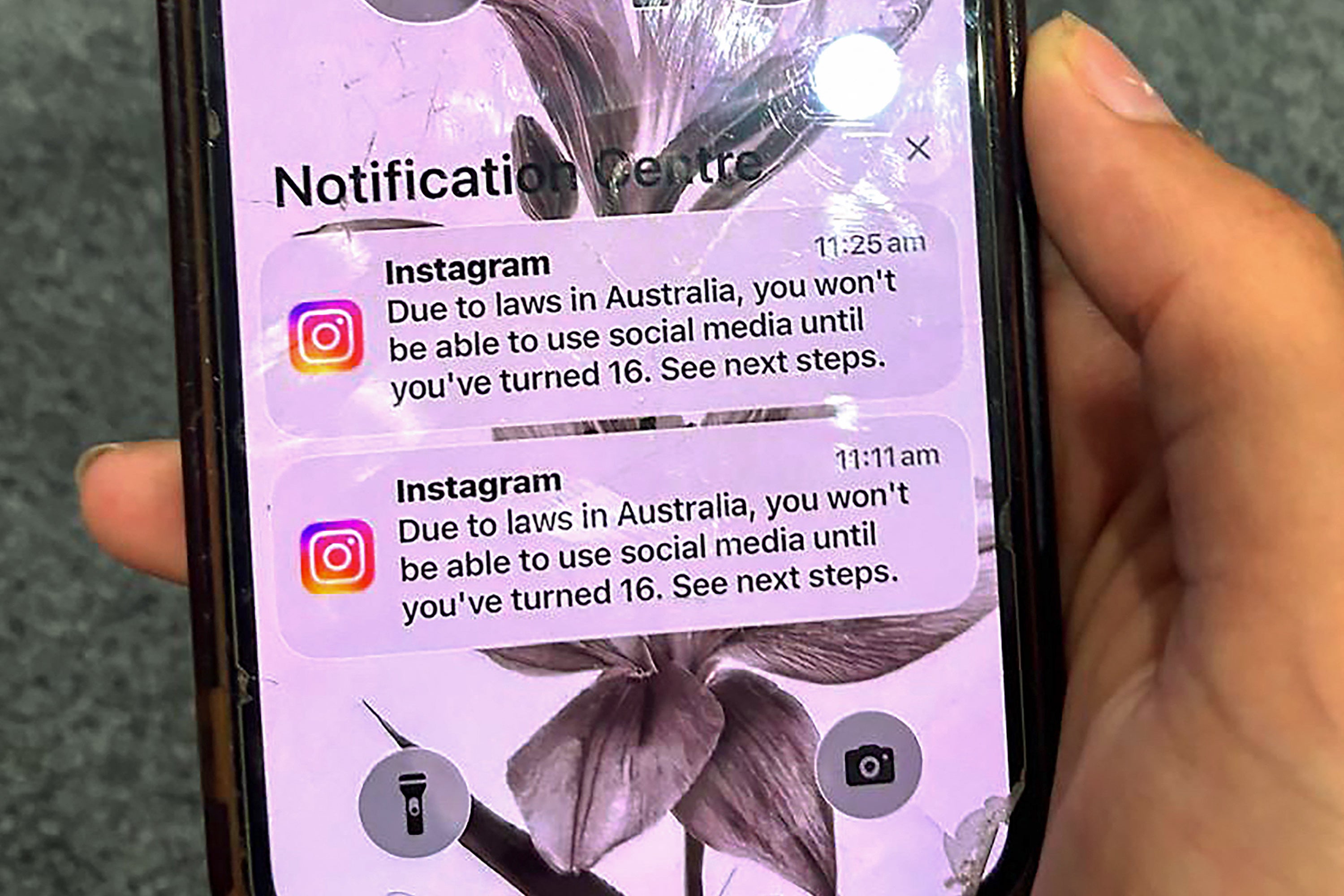 A teenager holds a mobile phone displaying a message from social media platform Instagram after their account was locked for age verification on 9 December 2025