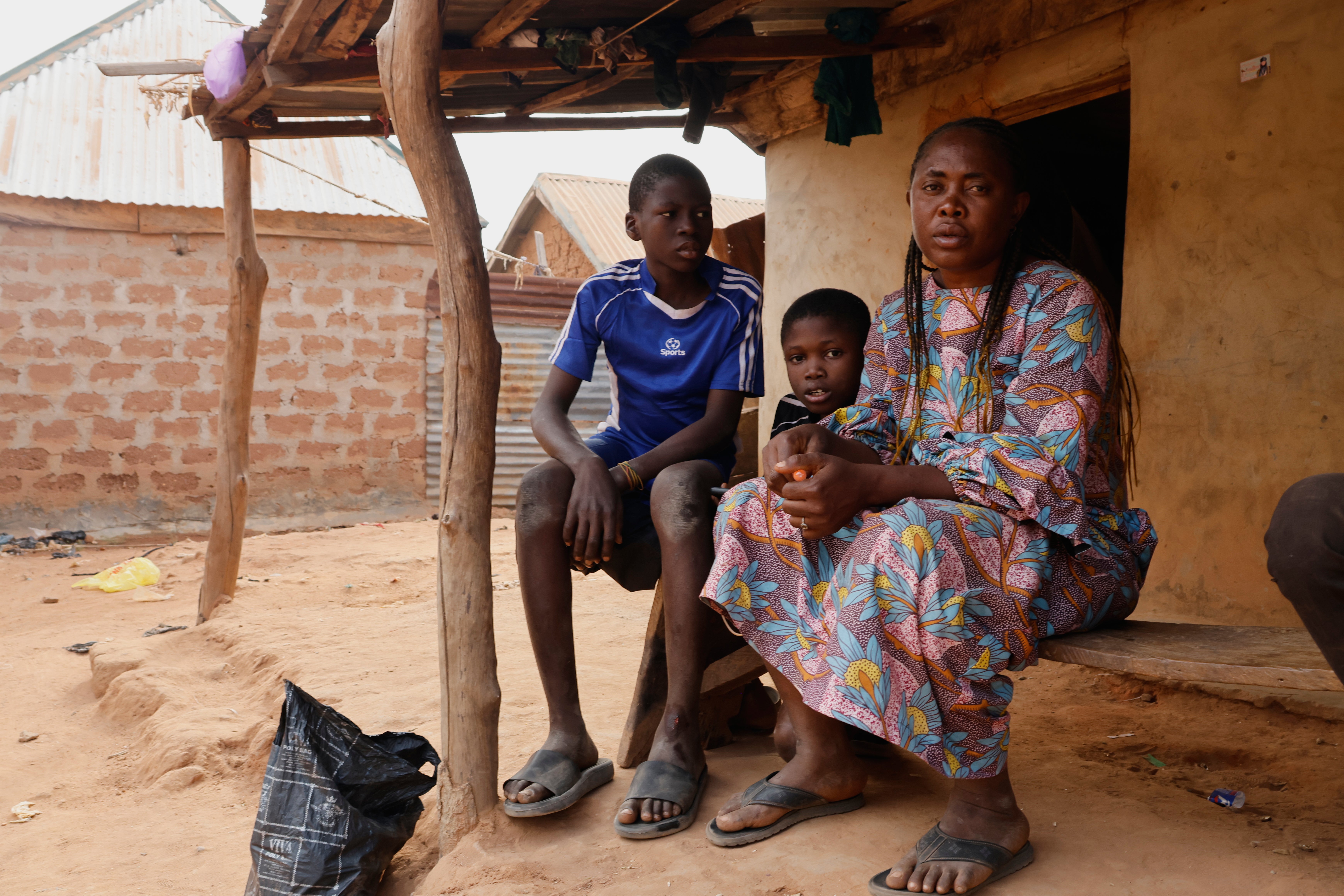 Precious Njikonye, right, the mother of a student at St. Mary’s Catholic School, who was abducted by gunmen and later released, sits outside her house in Papiri, Nigeria