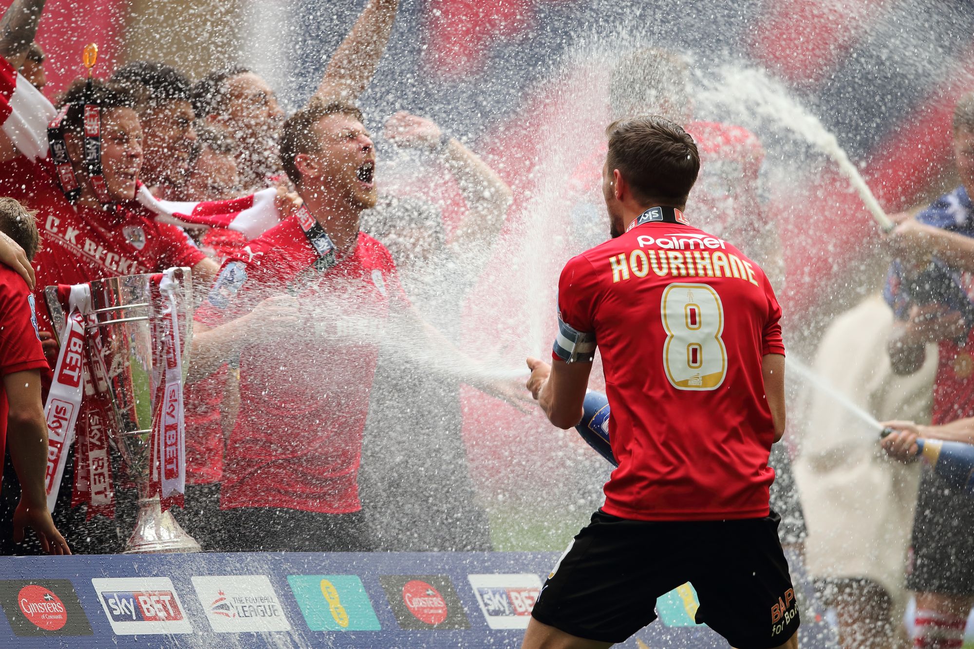 Conor Hourihane of Barnsley sprays champagne on his team mates as they celebrate promotion to the Championship