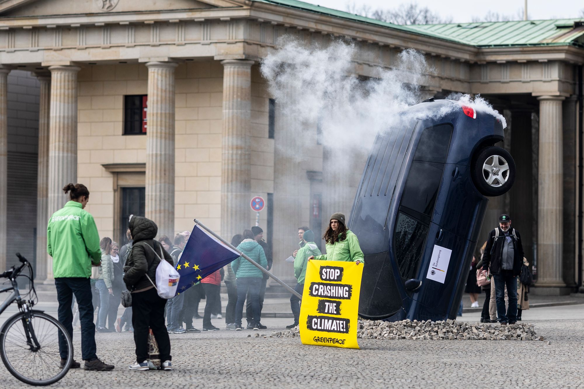 An installation by Greenpeace activists shows a SUV that is seemingly rammed into the pavement in front of the Brandenburg Gate on March 22, 2023 in Berlin, Germany, as the group protested the German government’s demand for an exception to new EU-wide legislation that would ban the sale of combustion engine cars by 2030