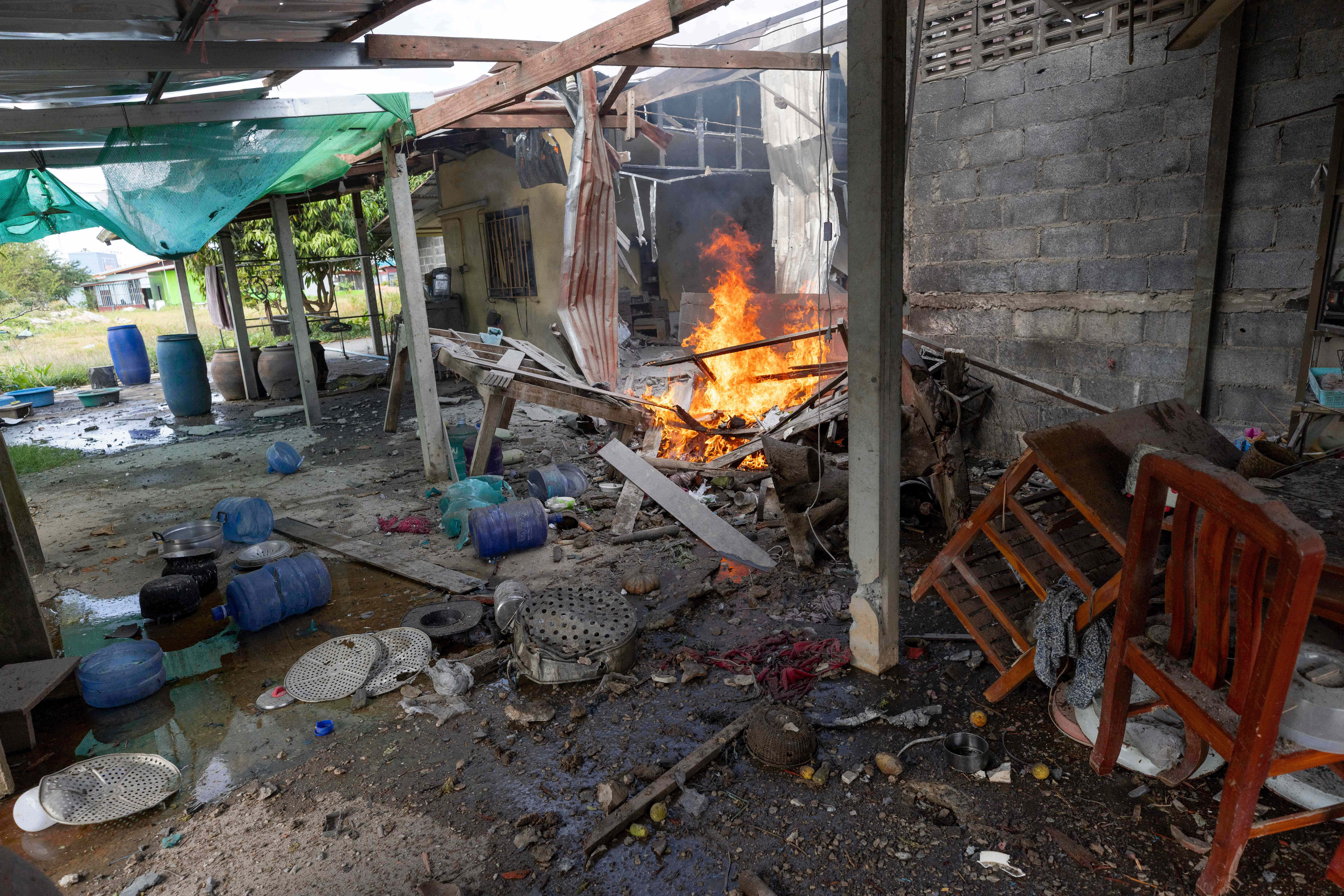 Flame rises from a house which, Thai local security forces say, was damaged by a Cambodian artillery in Surin province, Thailand