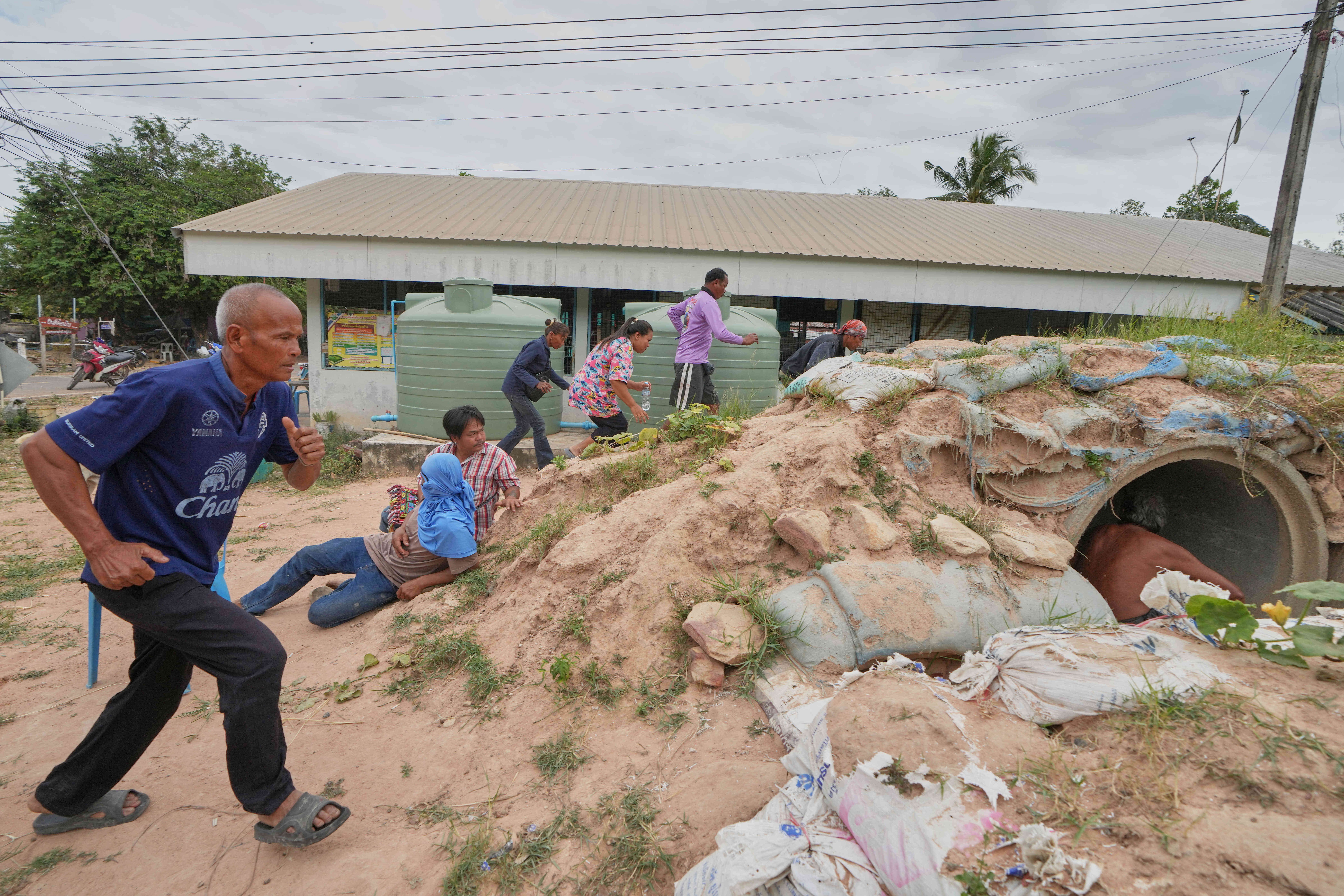 Village security volunteers and resident run into shelter while the blasts sounded too close in Buriram province, Thailand, Friday, 12 Dec 2025, following renewed border conflict between Thailand and Cambodia
