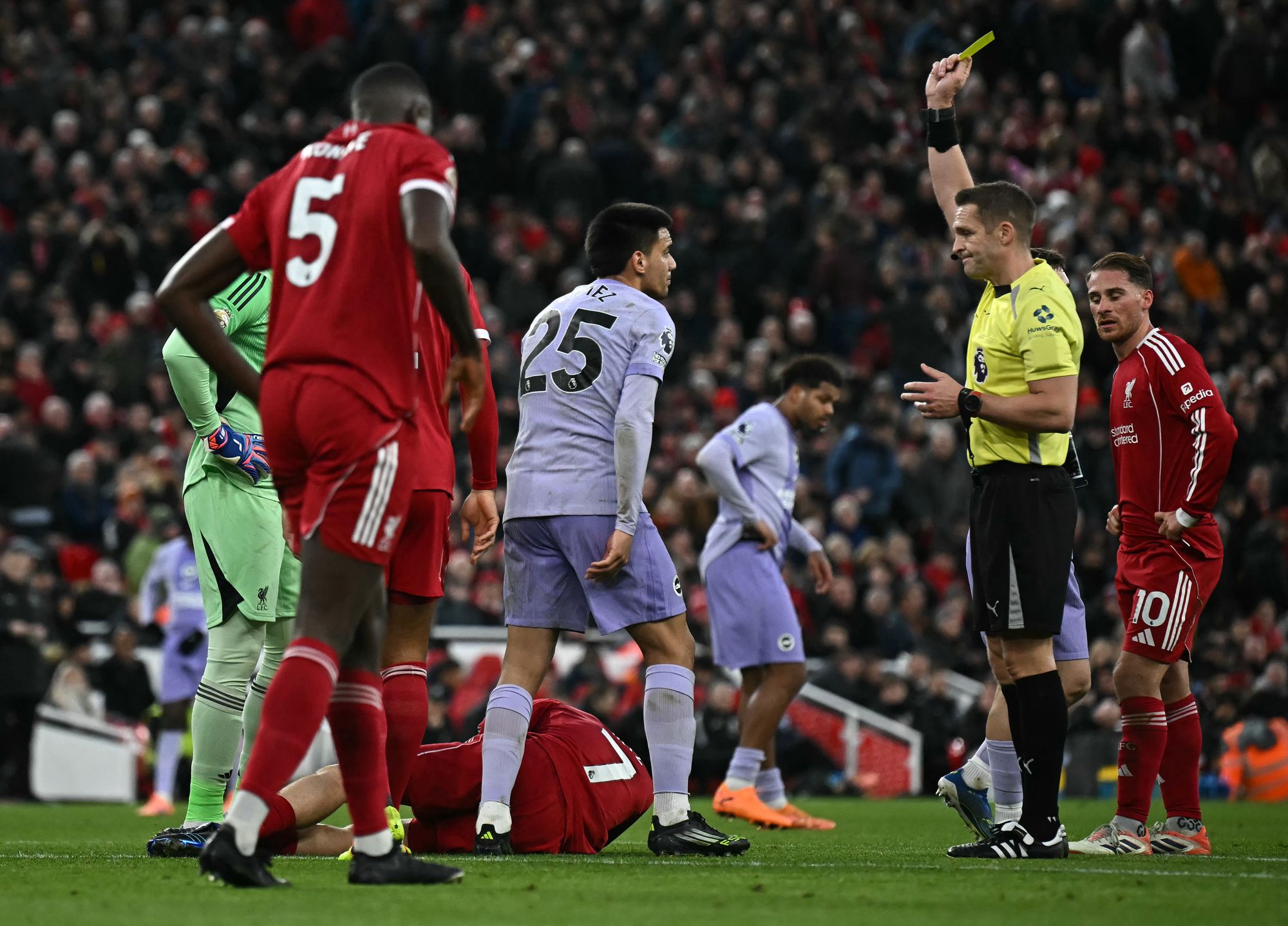 Referee Craig Pawson shows a yellow card to Brighton's midfielder Diego Gomez