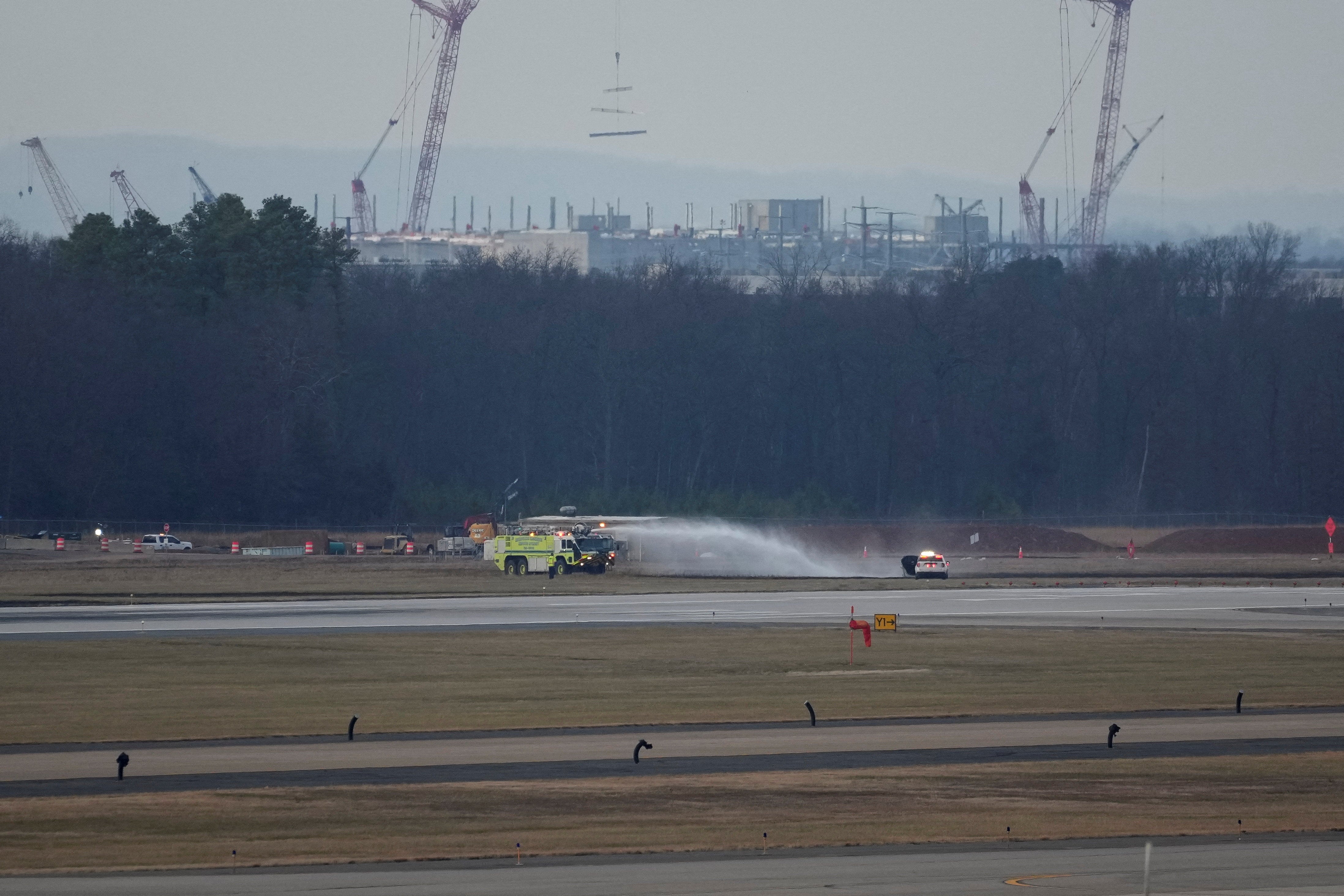 An emergency vehicle puts out a brushfire near the tarmac after United Airlines Flight 803's engine failed