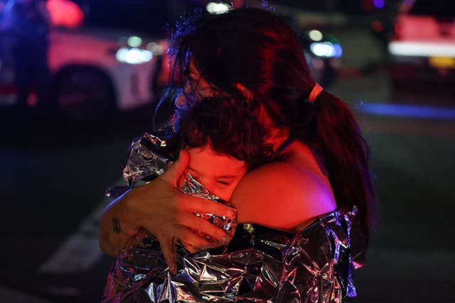 <p>A woman holds a child after the shooting at Bondi</p>