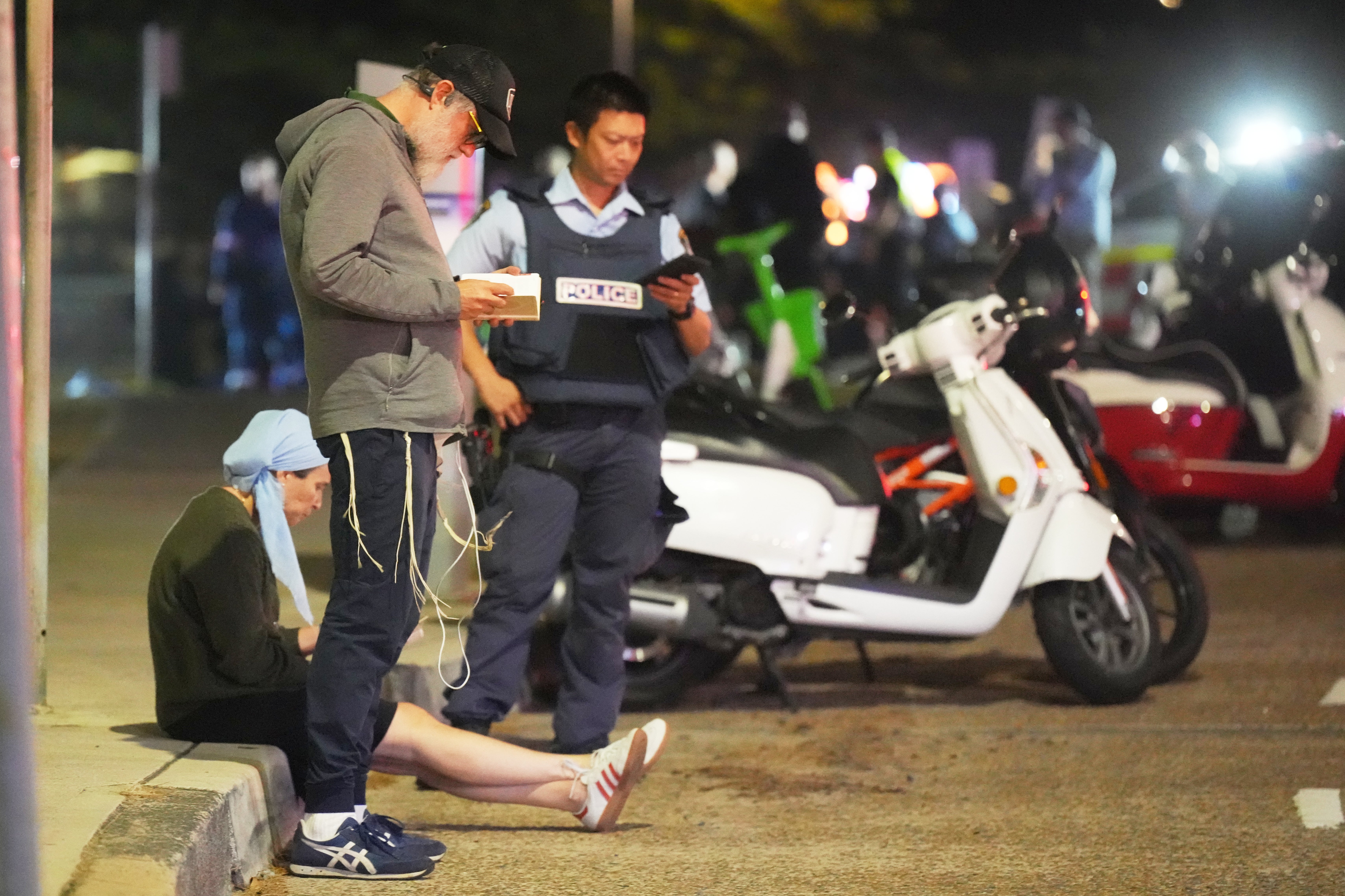 Bystanders stay where police cordon off an area at the Sydney beach